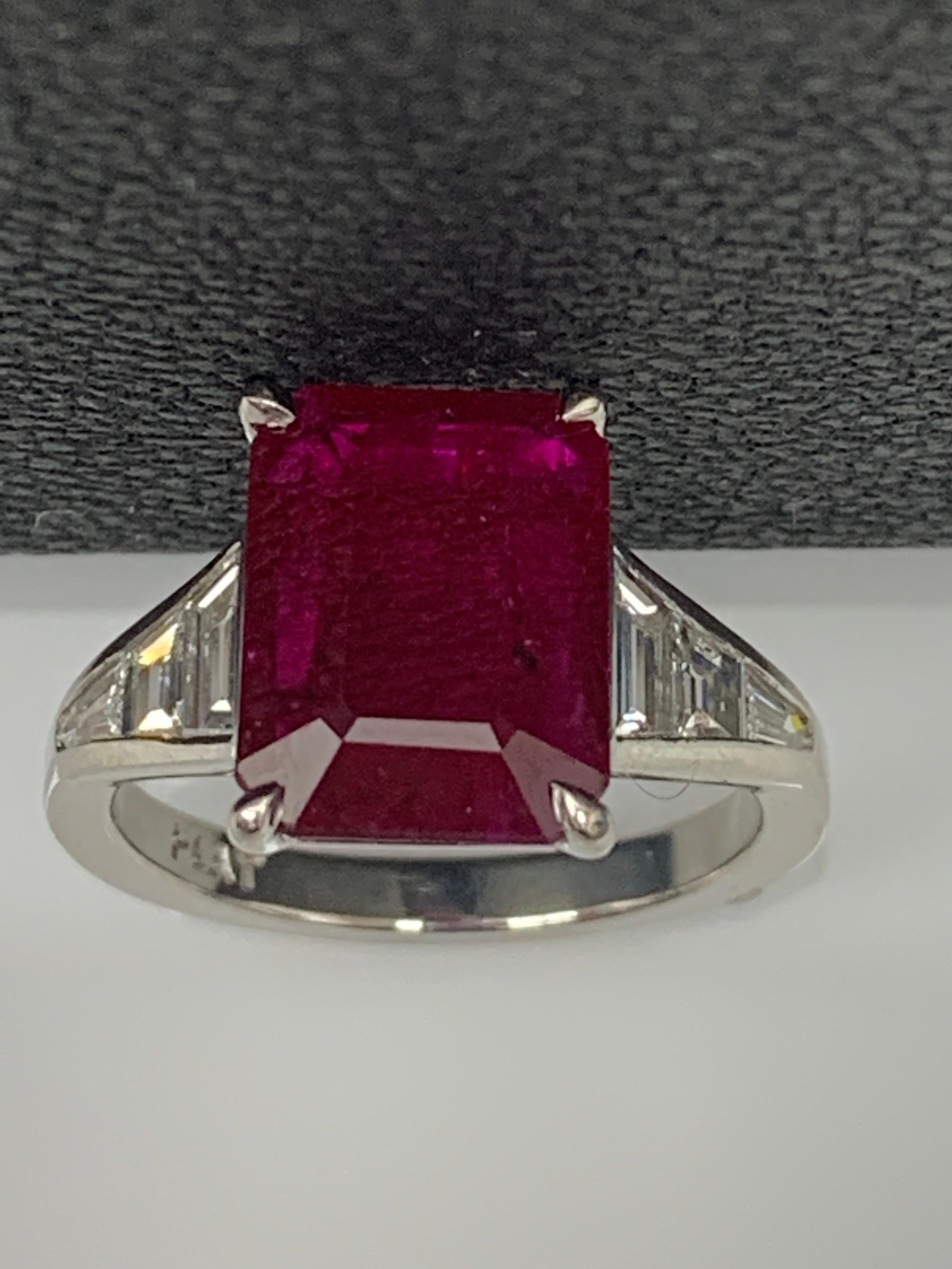 A stunning well-crafted engagement ring showcasing a 3.87-carat  emerald-cut Ruby. Flanking the center diamond are perfectly matched graduating step-cut diamonds, channel set in a polished platinum mounting. 6 Accent diamonds weigh 0.66 carats in