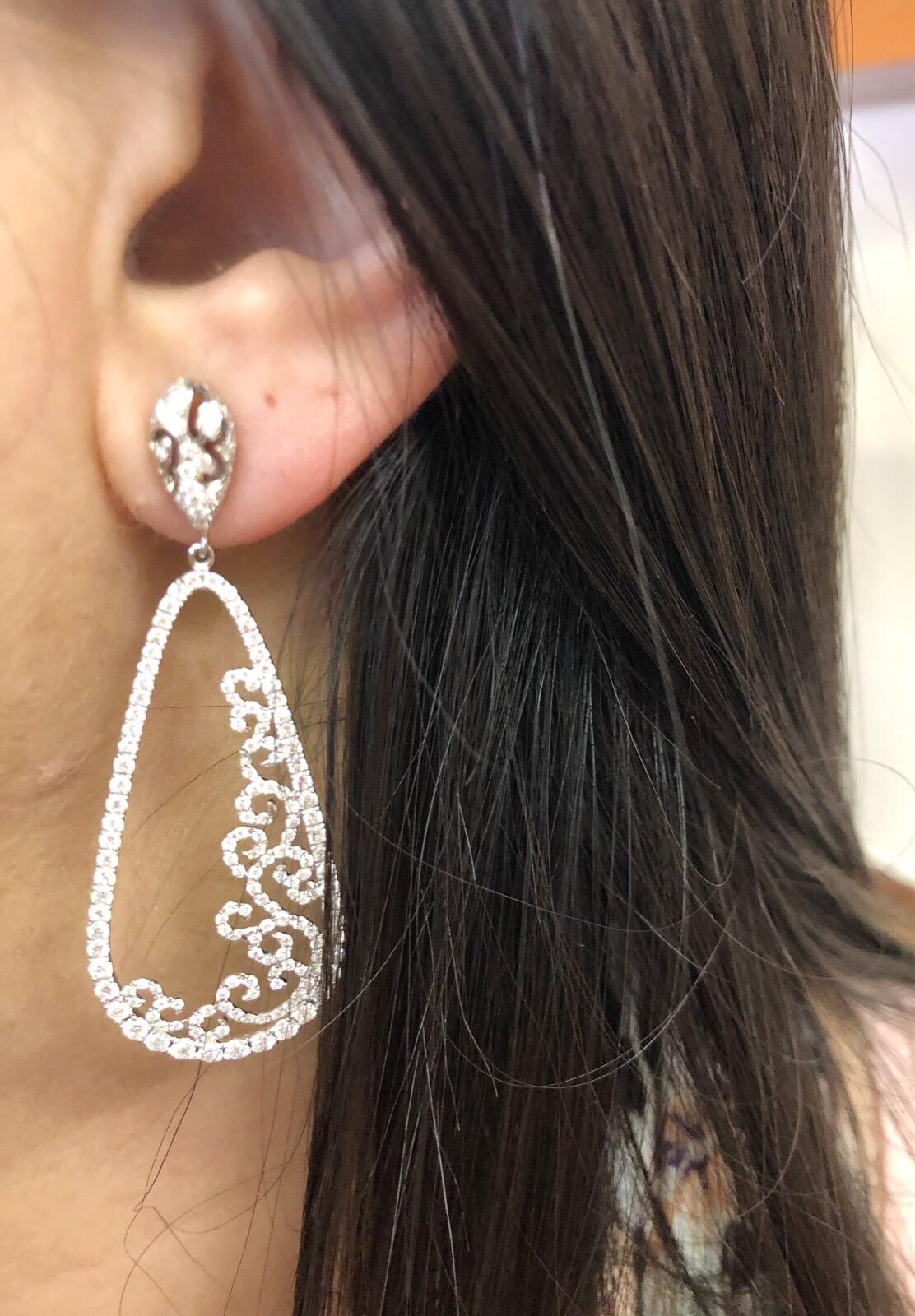3.88 Carats total weight of round brilliant prong-set diamonds set in 18K white gold drop scrolled earrings in a tear drop shape. Diamond quality: F-H color, VS2-SI1 clarity.