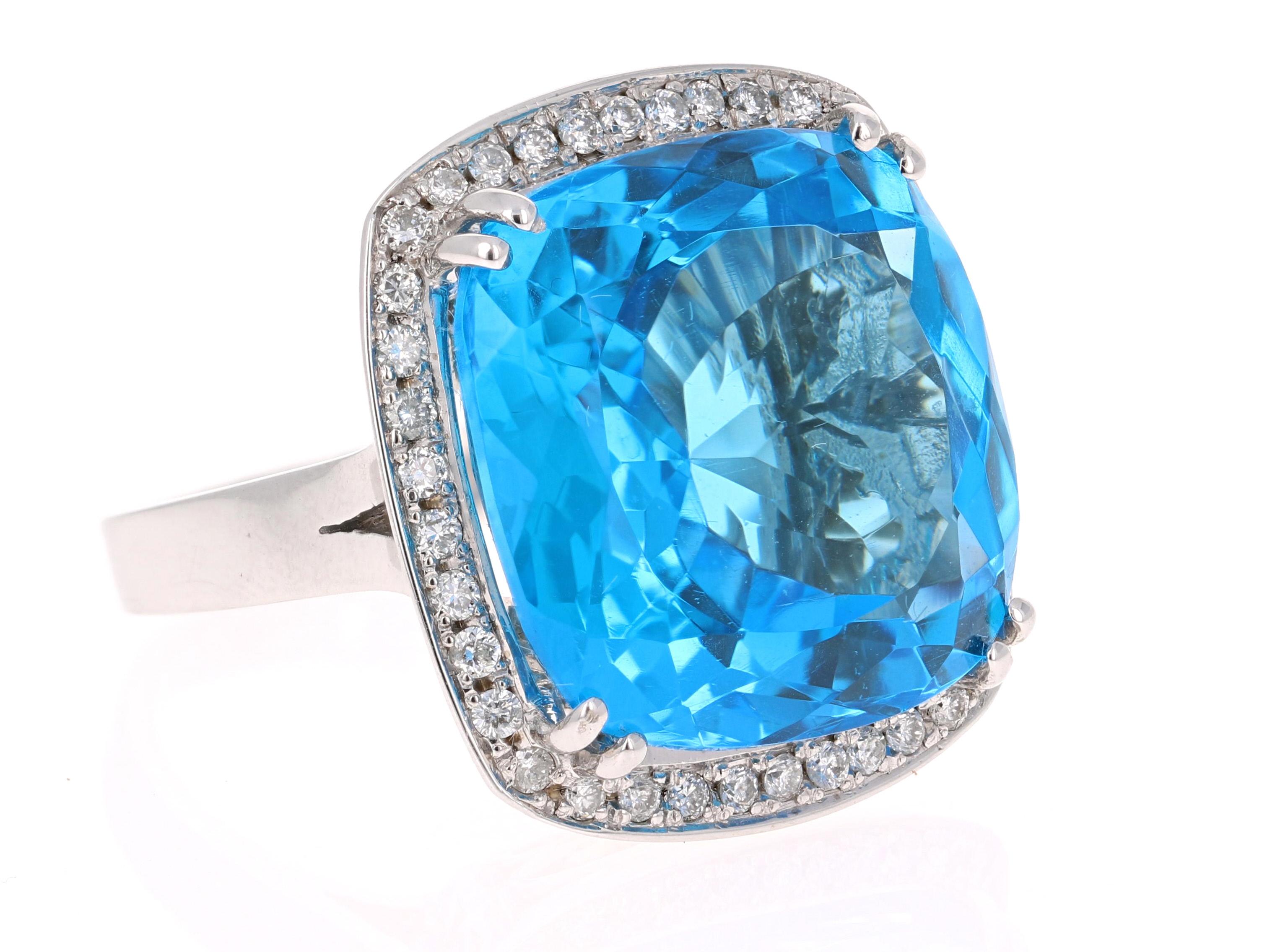 This stunning statement ring has a large Cushion Cut Blue Topaz that weighs 38.19 Carats. 
It is surrounded by a simple halo of 36 Round Cut Diamonds that weigh 0.63 Carats. The clarity and color of the diamonds are SI-F. 

It is crafted in 14 Karat
