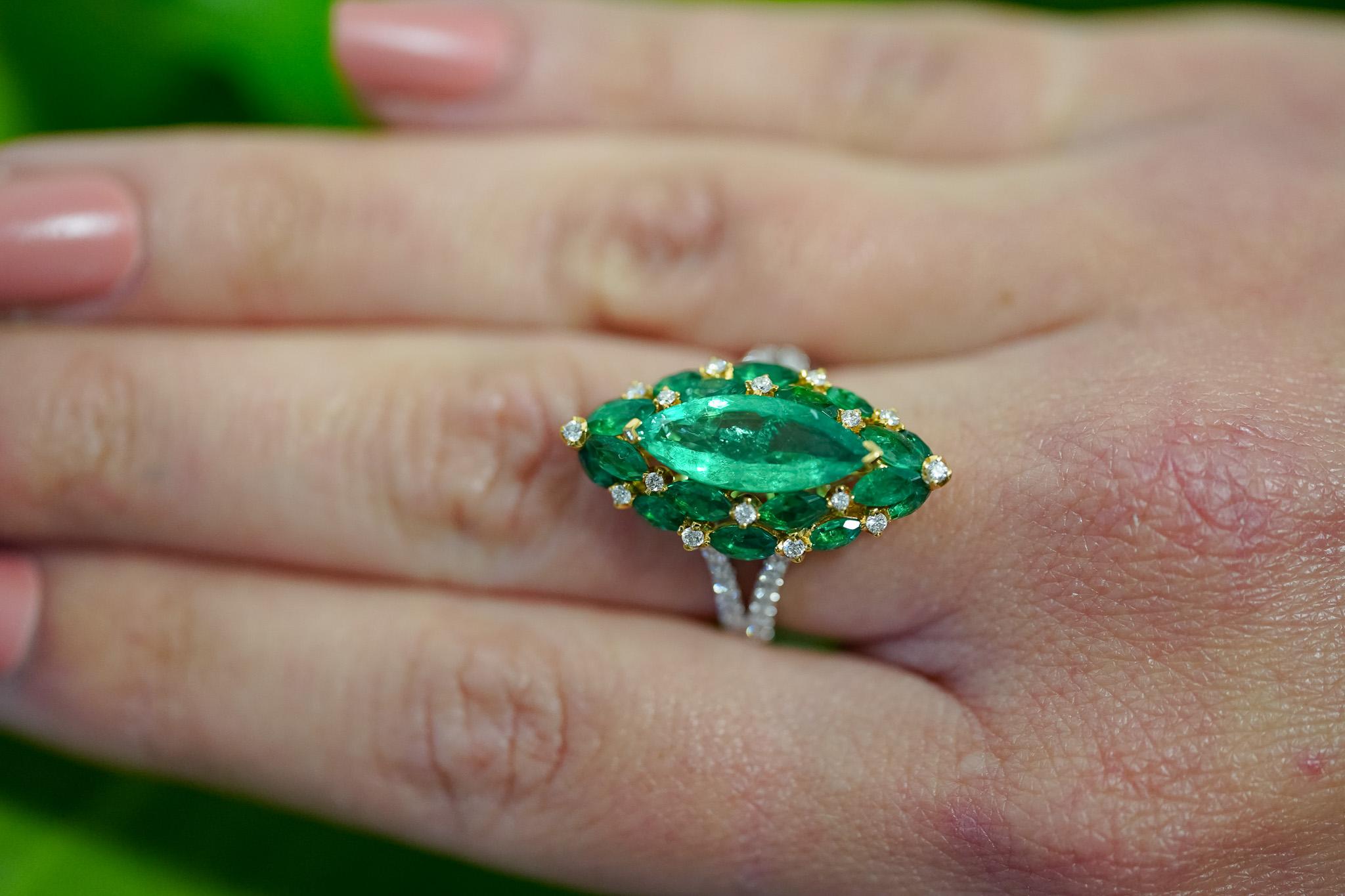 Marquise cut natural emerald and diamond ring in 18k gold. Featuring a vivid green 1.96 carat Colombian emerald center stone. Flanked by a gorgeous cluster of marquise Colombian emeralds and round diamonds. Each Emerald is mounted with sharp 18k