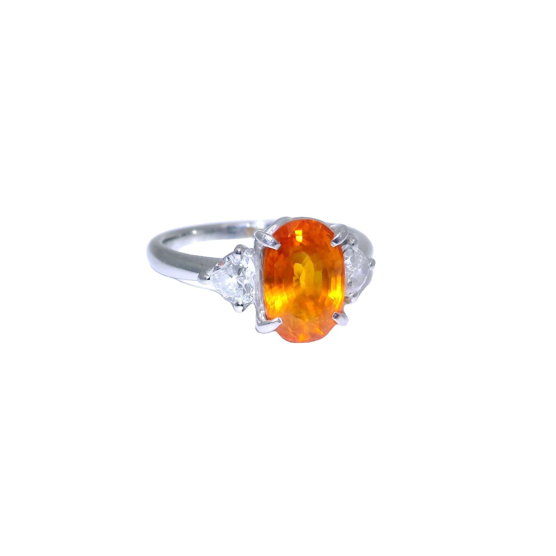Ein auffälliger Dreisteinring mit einem exquisiten ovalen orangefarbenen Saphir mit einem Gewicht von 3,89 Karat und einer der stärksten reinen Orangetöne, die wir je bei einem natürlichen Saphir gesehen haben. Die Farbe ist ein reines Orange mit
