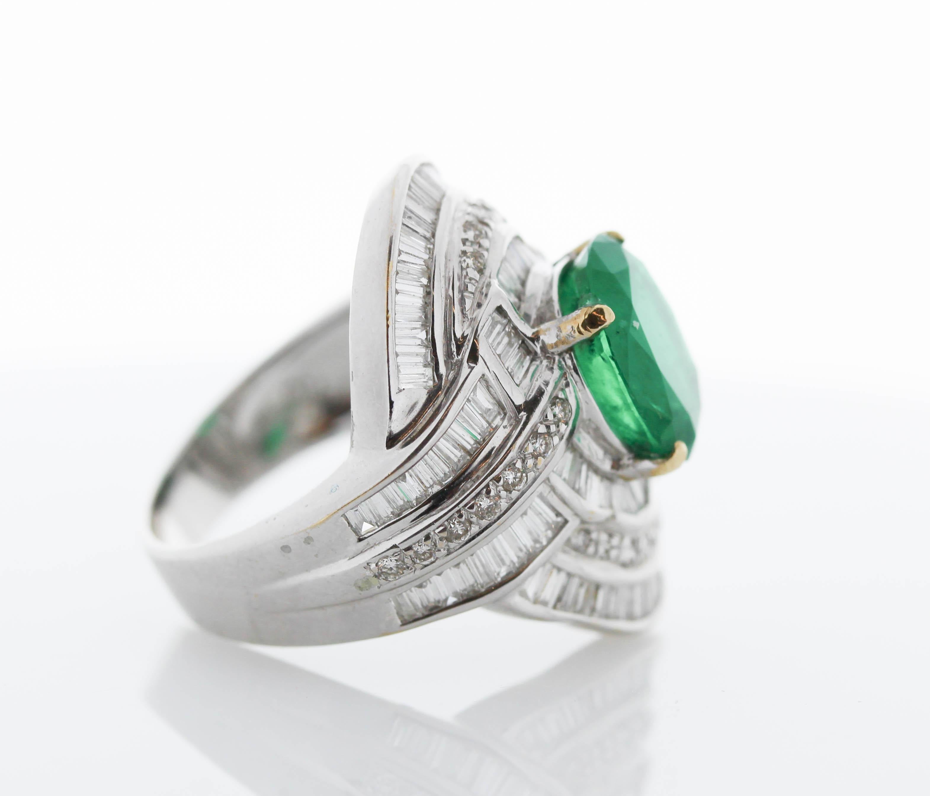 Remarkable in craftsmanship and design, this gorgeous 18k white gold emerald and diamond ring is undeniably unique. An oval cut fine quality emerald sits in the center secured in a prong setting with a weight of 3.89 carats and measures 11.1 X9.3MM.