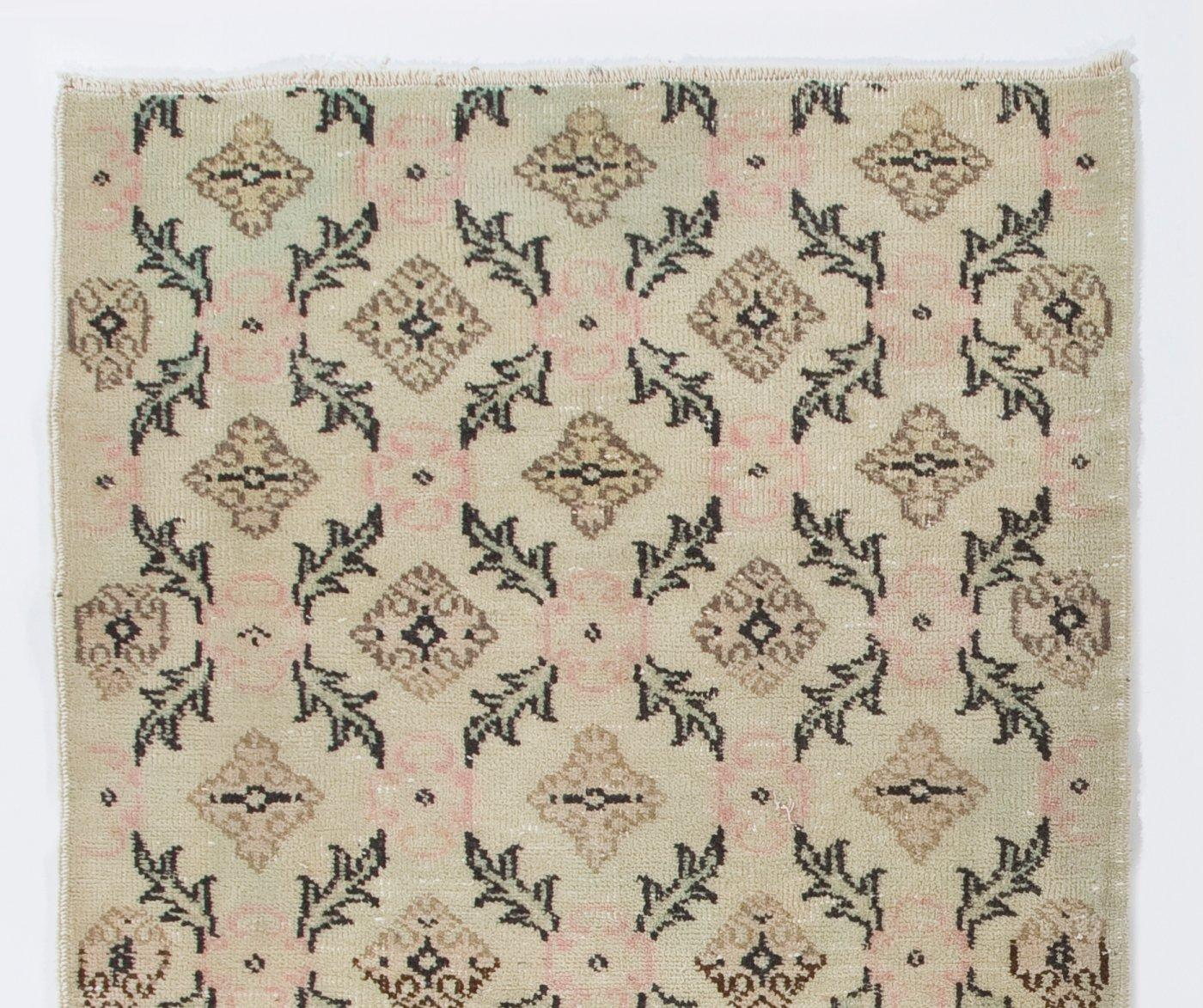 A vintage Turkish accent rug in beige, brown, black, green and pink colors. It was hand-knotted in the 1960s and floral design. Low wool pile on finely woven cotton foundation. Sturdy and can be used on a high traffic area, suitable for both
