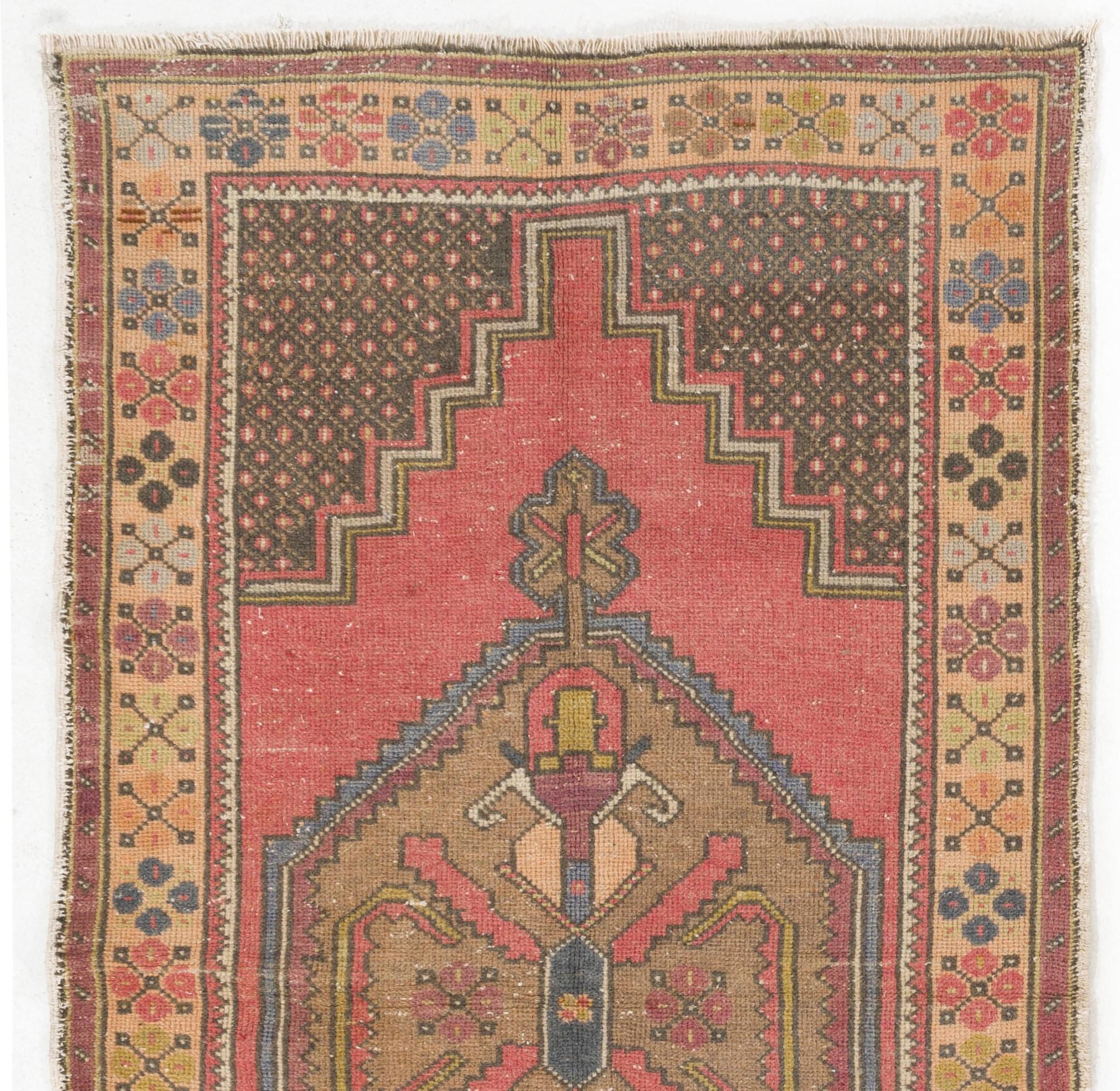 This vintage Central Anatolian rug features two linked medallions in deep-saturated gold with cross-shaped motifs inside against a plain field in soft muted soft red. The corner-pieces in charcoal gray are decorated with large, elongated palmettes.