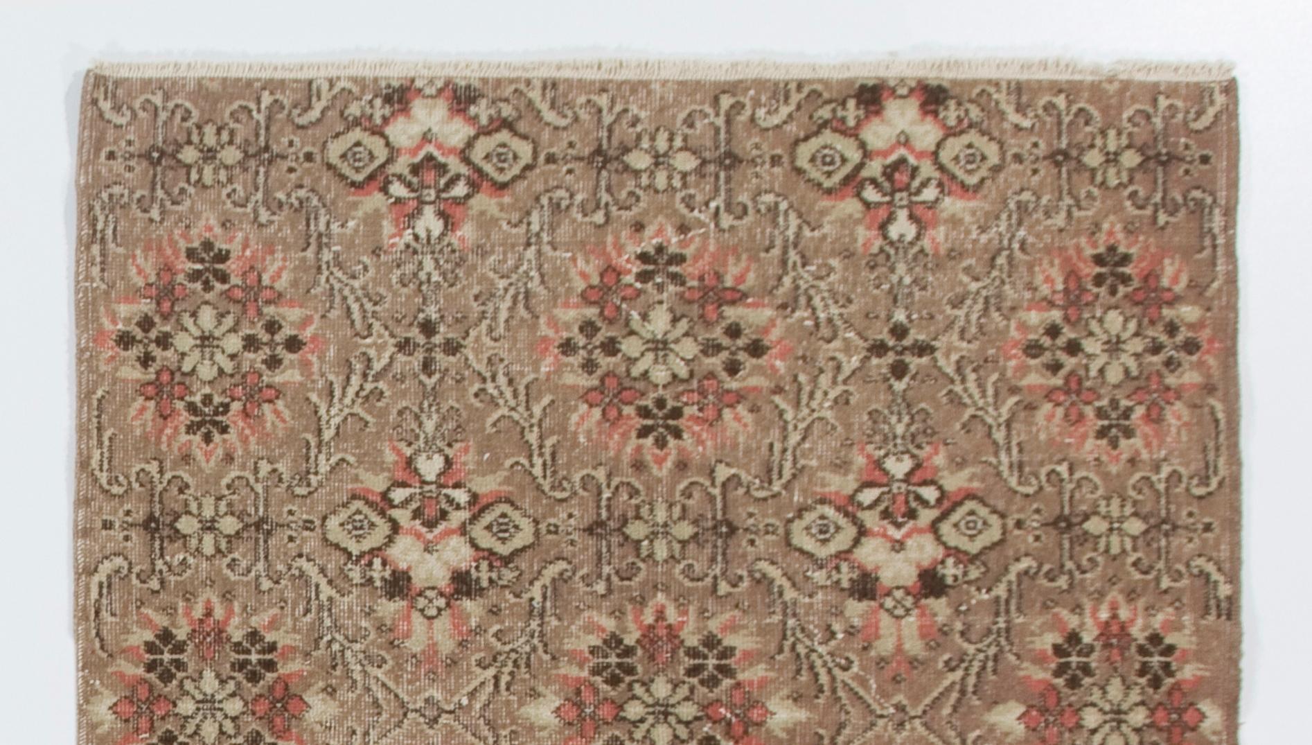 This vintage hand knotted Turkish rug was originally made in the 1960s. It features an all-over latticed floral design in coral pink and taupe. It has medium wool pile on cotton foundation, is in good condition, sturdy and clean as a brand new rug.