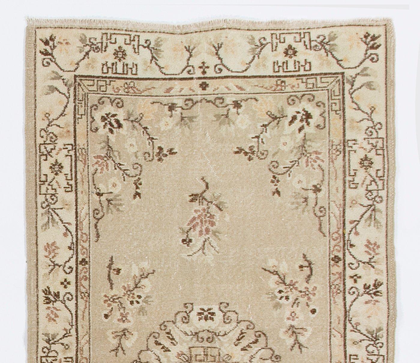 Ce tapis turc vintage des années 1960, finement noué à la main, présente un motif chinois Art Deco composé d'un médaillon central composé de motifs floraux et de vignes en spirale, de vignes florales flottantes d'aspect réaliste en brun, ivoire et
