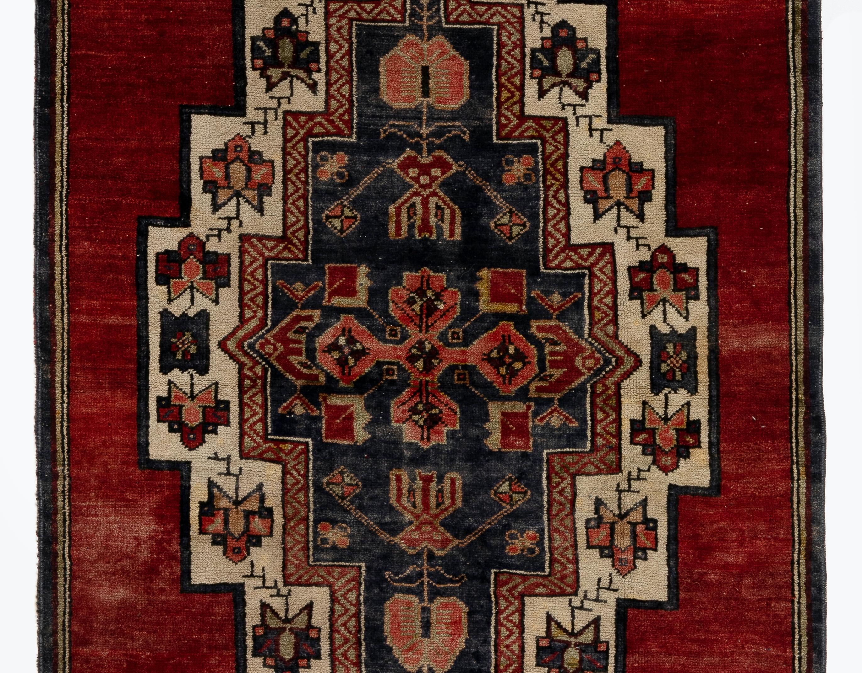 A vintage village rug from Turkey. It features a large, elaborate medallion against a deep rich red background and an outer frame in dark navy.
Finely hand-knotted with even medium wool pile on wool foundation. Very good condition. Sturdy and as