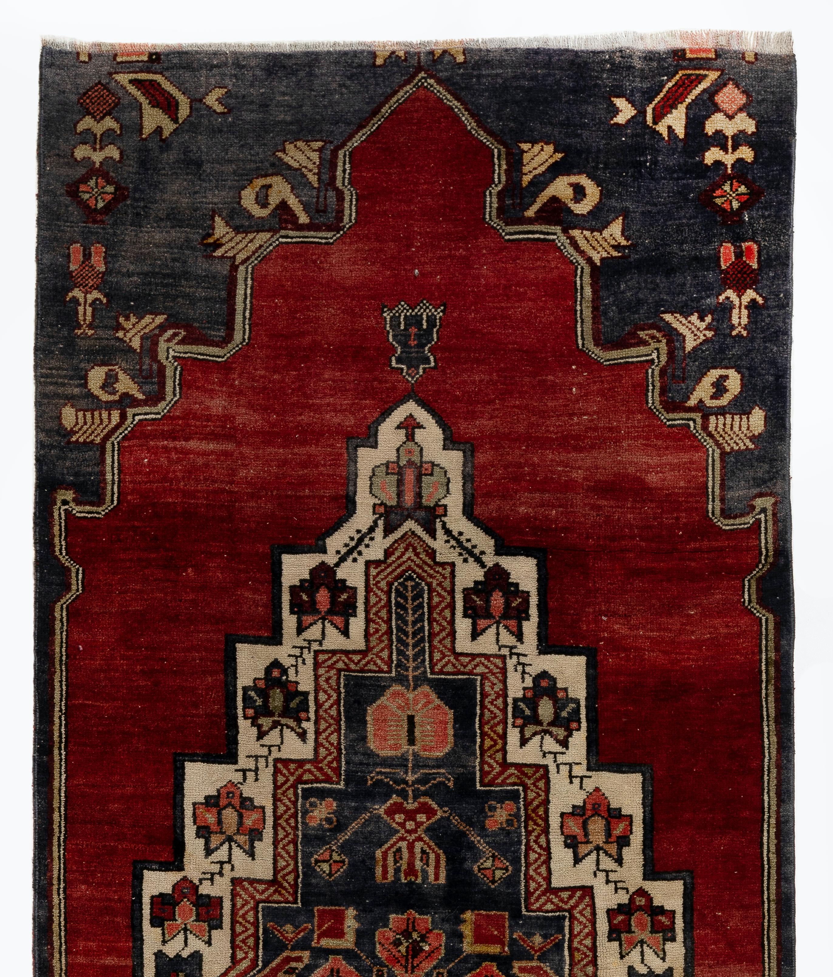 A vintage village rug from Turkey. It features a large, elaborate medallion against a deep rich red background and an outer frame in dark navy.
Finely hand-knotted with even medium wool pile on wool foundation. Very good condition. Sturdy and as