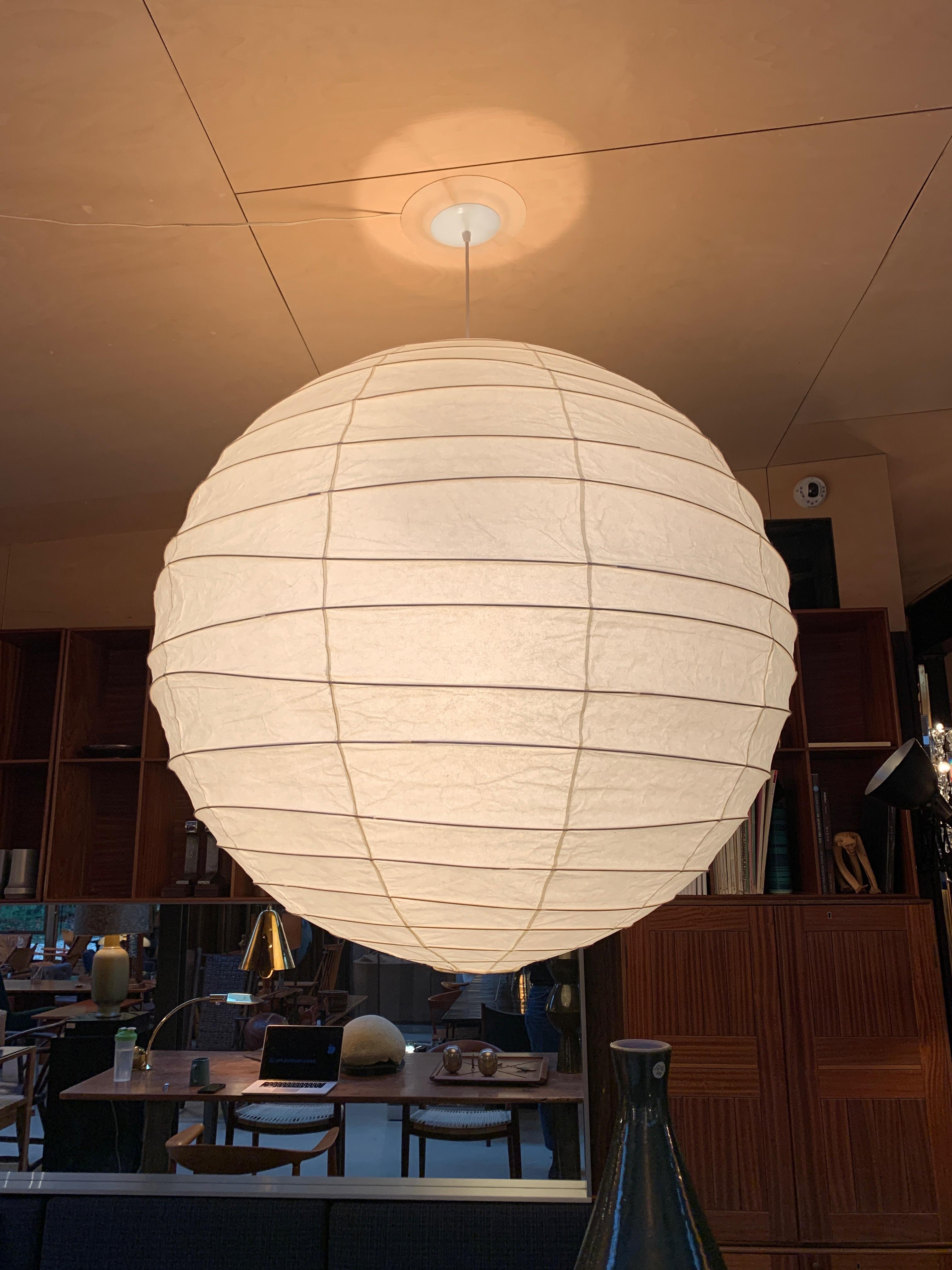 A hanging round Akari lighting sculpture and lantern, handcrafted from washi paper and bamboo ribbing. Designed by Isamu Noguchi in 1951 and manufactured in Gifu, Japan. Measures: 39