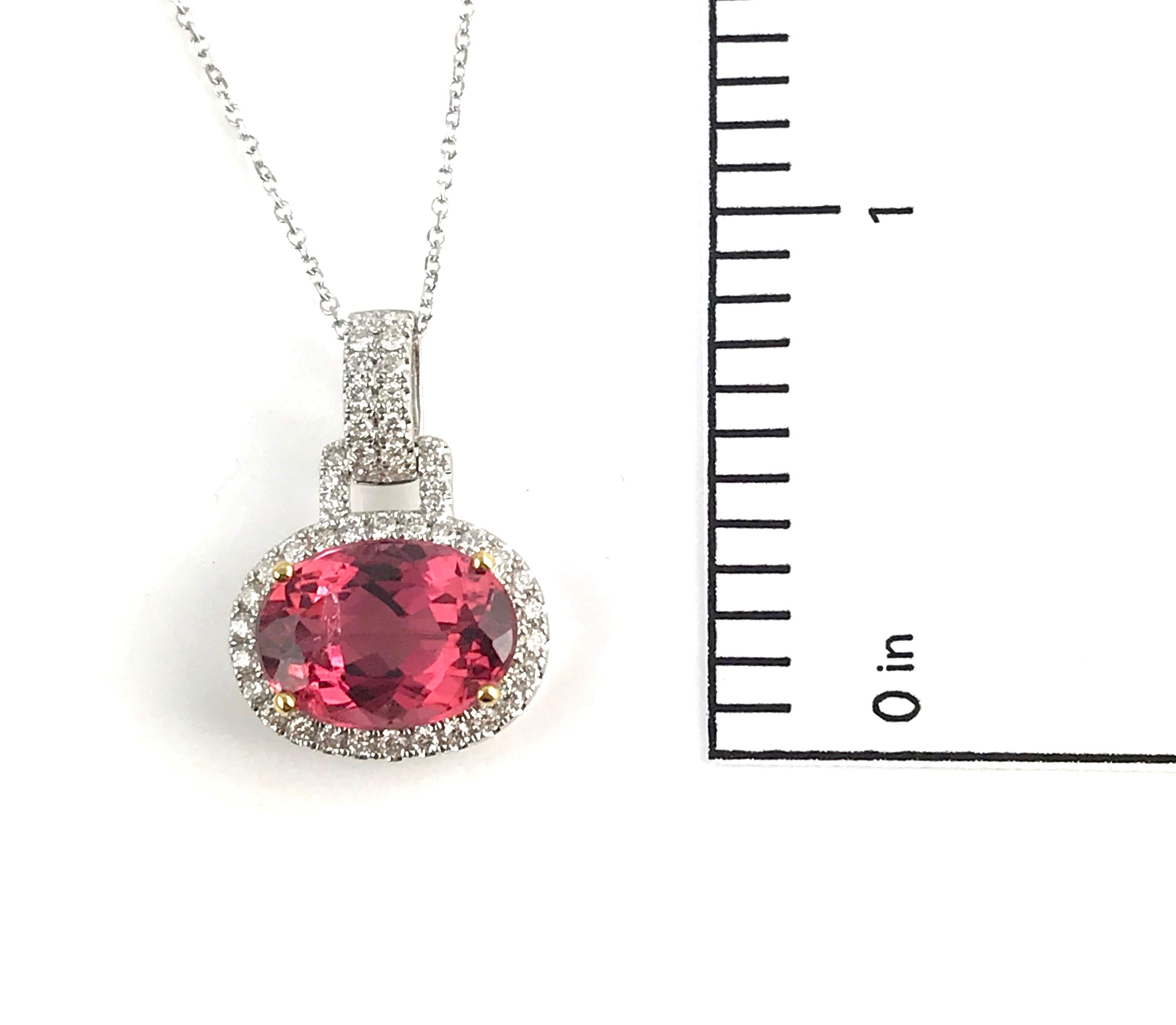 This striking pendant boasts a 3.90 carat oval-cut raspberry pink tourmaline centerpiece, elegantly nestled in an 18k yellow gold setting, and encircled by a halo of round white diamonds. The central gem is further accentuated by a surrounding halo