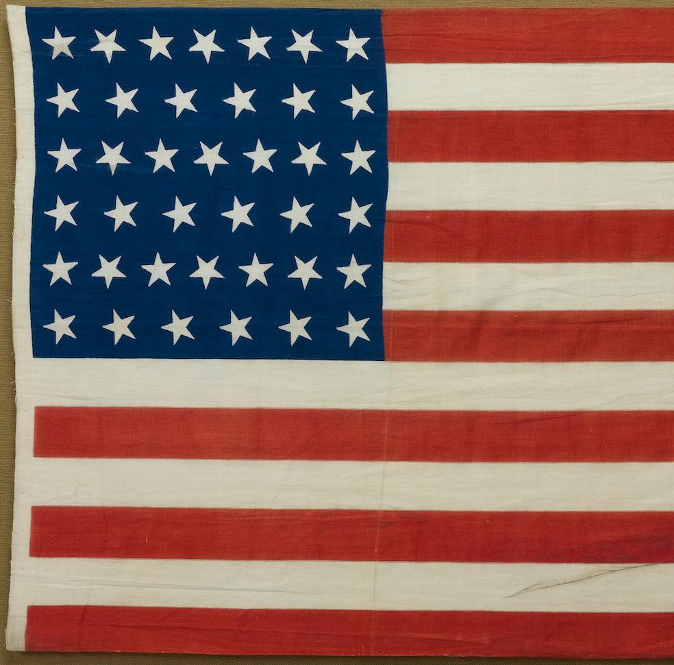 Dies ist eine inoffizielle amerikanische Flagge mit 39 Sternen, handgefertigt und auf Baumwolle gedruckt. Die Flagge stammt aus dem Jahr 1889 und hat dank ihrer seltenen Sternenzahl eine einzigartige Geschichte.

Der Kanton der Flagge ist in einem