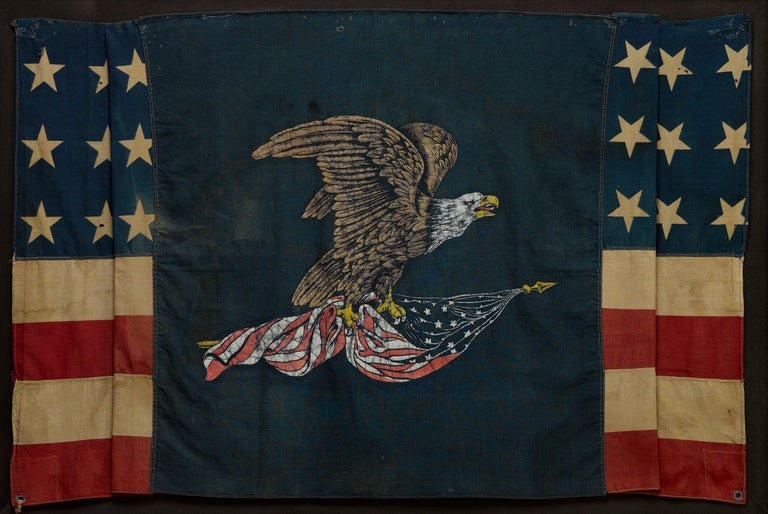 Presented is a stunning, 39-star patriotic banner commemorating North Dakota statehood. A large and dramatic polychrome eagle is printed on the center of a dark blue cotton field. The bald eagle is depicted mid-flight and clutches an American flag