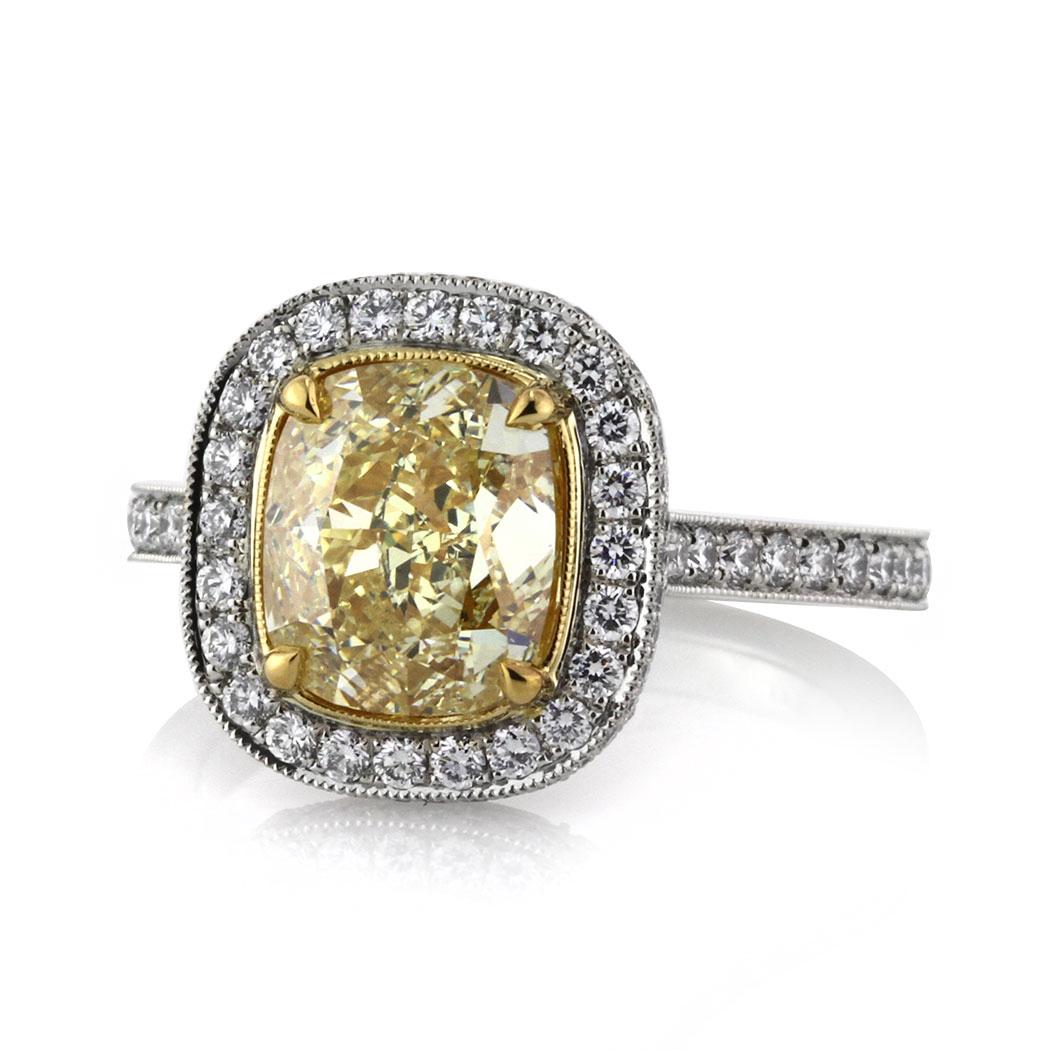 This alluring diamond engagement ring showcases a stunning 3.00ct cushion cut center diamond, GIA certified at Fancy Yellow-VS2. It is accented by a halo of white round brilliant cut diamonds as well as one row of sparkling diamonds micro pavé set