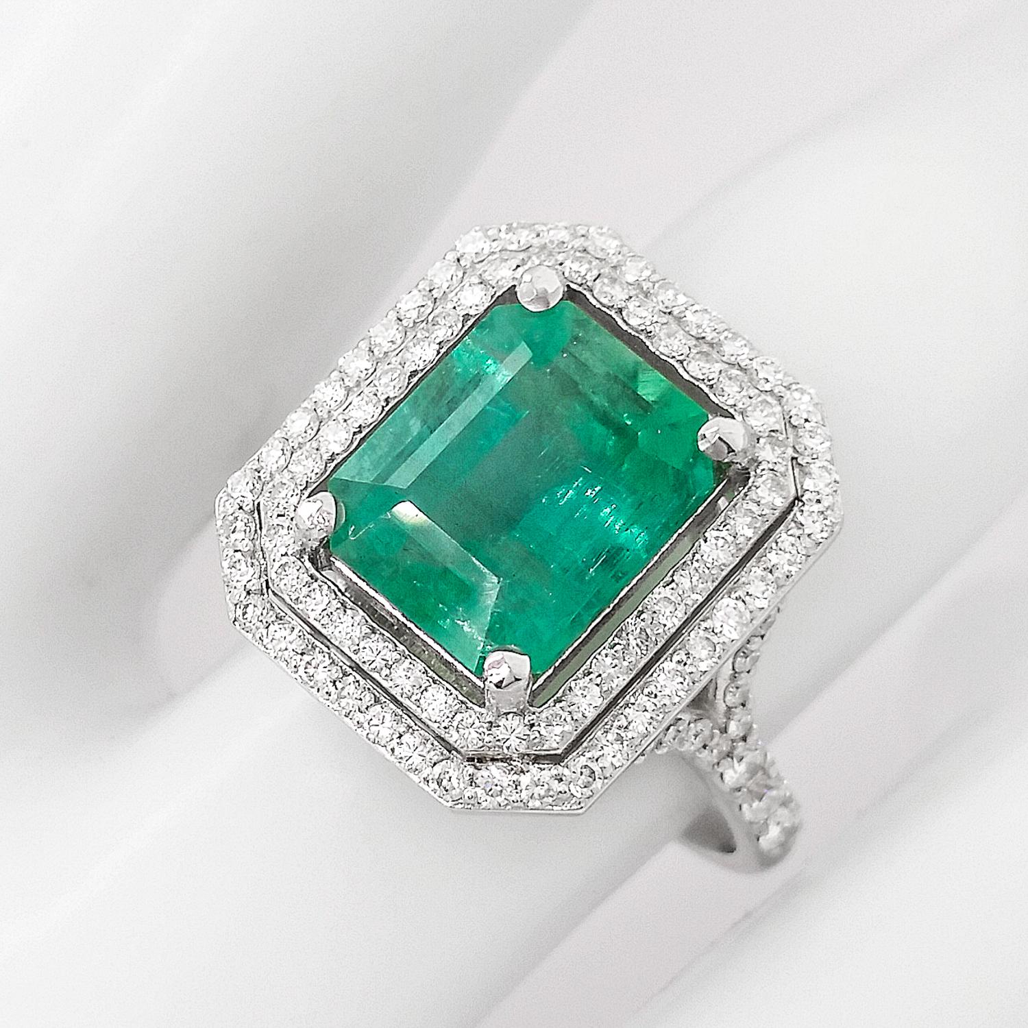 Two rows of 98 endlessly sparkling round brilliant diamonds, totaling 0.70 carats, harmonically surround the gorgeous bluish-green natural green emerald weighing 3.24 carats, and all set in 14kt white gold. This amazing ring has a unique design and