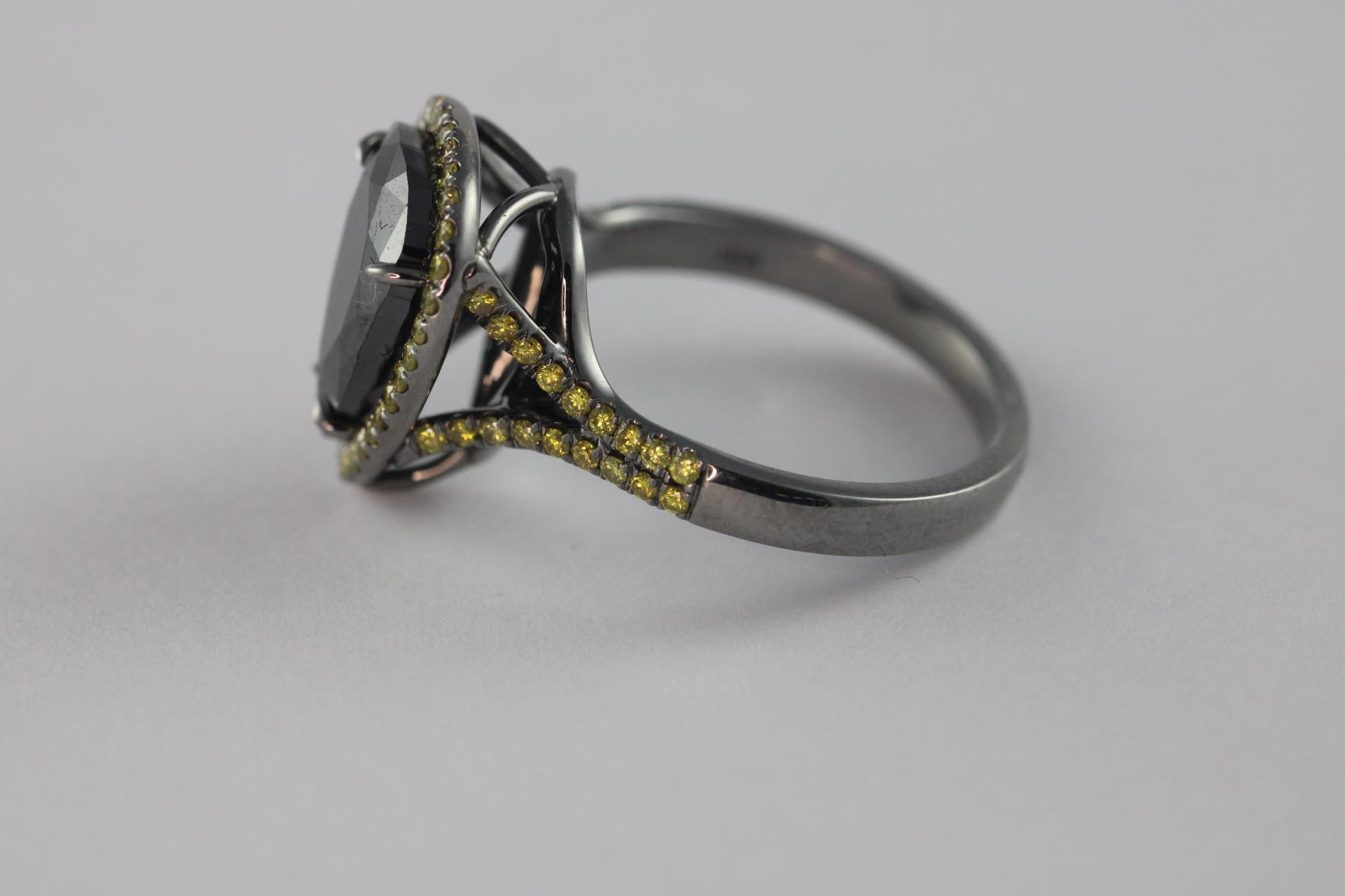 Un diamant noir naturel en forme de poire mesurant 3,95 carats est au centre de cette bague exquise, entouré d'un halo de 67 diamants ronds naturels de couleur jaune fantaisie totalisant 0,46 carats. Serti dans un anneau en or blanc 18 carats à tige
