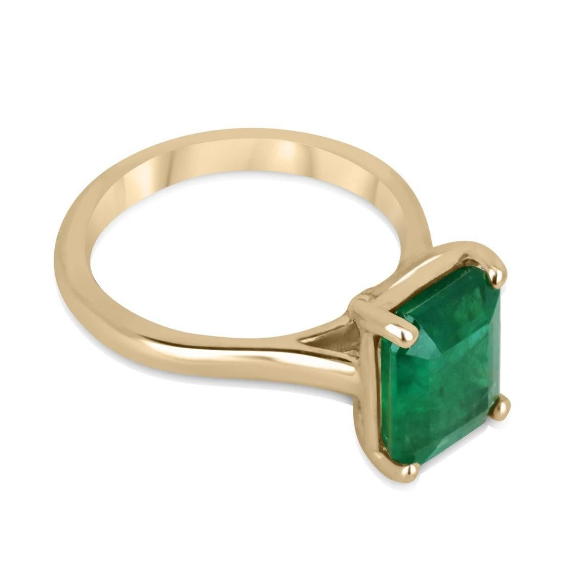 This stunning solitaire ring boasts a remarkable 3.95-carat emerald as its centerpiece, exuding timeless elegance and sophistication. The emerald cut stone has a gorgeous rich green color with a yellowish-green hue, and very good luster, making it a