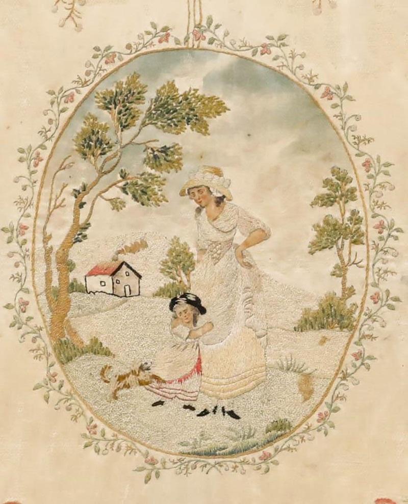 A charming Georgian silk embroidery panel depicting a mother and child walking through the countryside, accompanied by their faithful dog. Executed with remarkable skill, the artist has rendered this idyllic scene with meticulous attention to