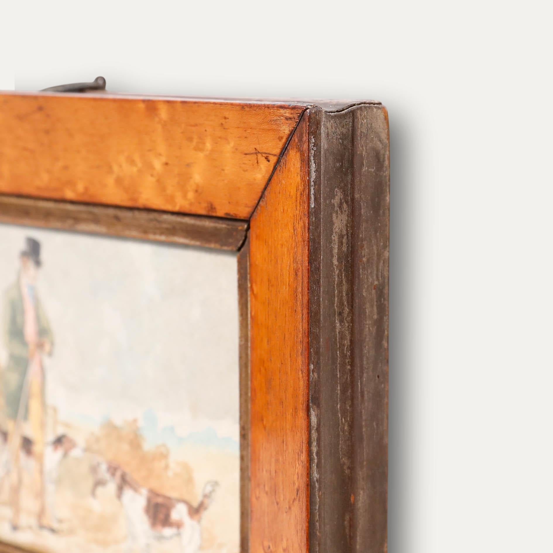 Un caballero finamente vestido limpia el cañón de su rifle de caza mientras sus perros esperan a sus pies, uno de ellos con una pieza recién cazada en las fauces. Presentado en un marco de madera vintage. Sin firmar. Sobre el papel.