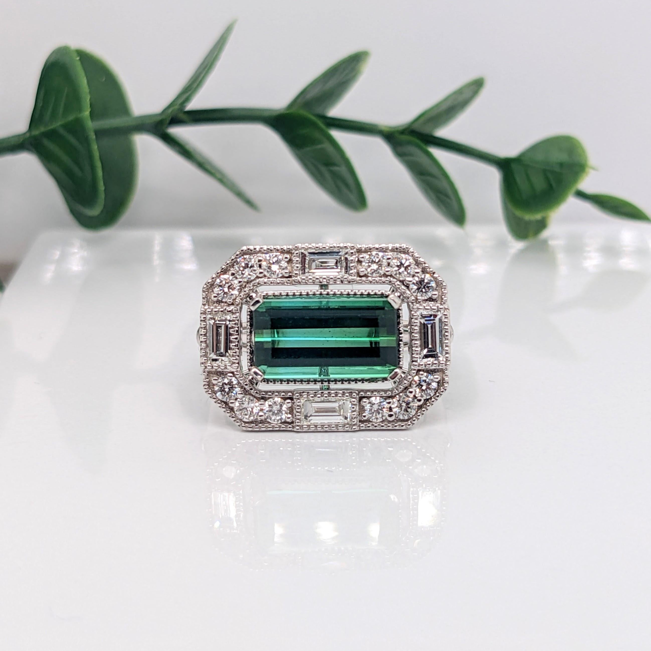 A vivid green Chrome Tourmaline looks exquisite in this Art Deco engagement/statement ring with features of fine Milgrain detailing, a mixed baguette and round diamond halo on east west basket and an embellished pave diamond shank. Chrome Tourmaline