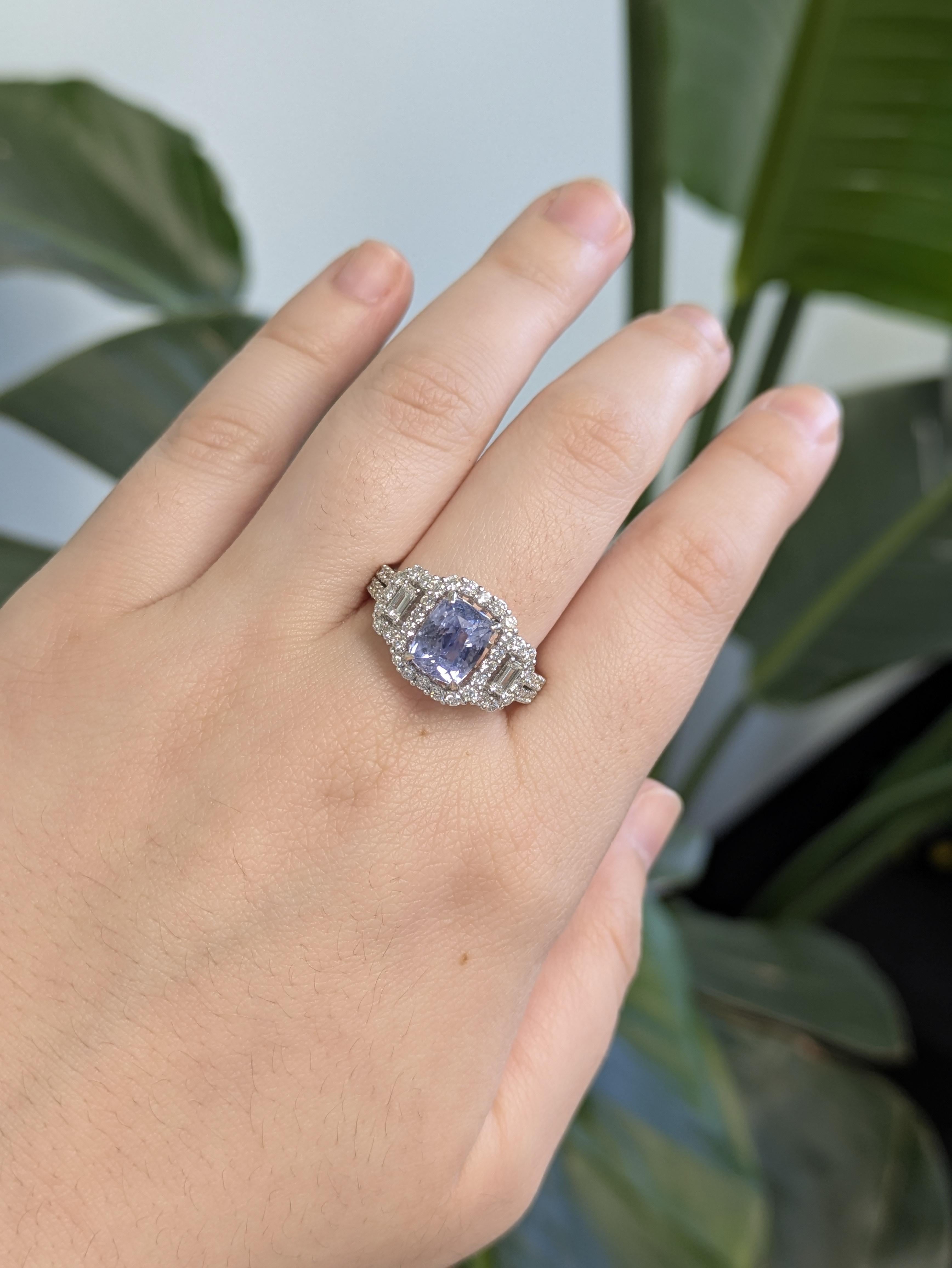 Cette bague exquise présente en son centre un saphir bleu bleuet captivant, entouré d'un halo de diamants naturels. Agrémenté de diamants baguettes et ronds, il est réalisé en or blanc massif 14k pour une élégance intemporelle et une sophistication