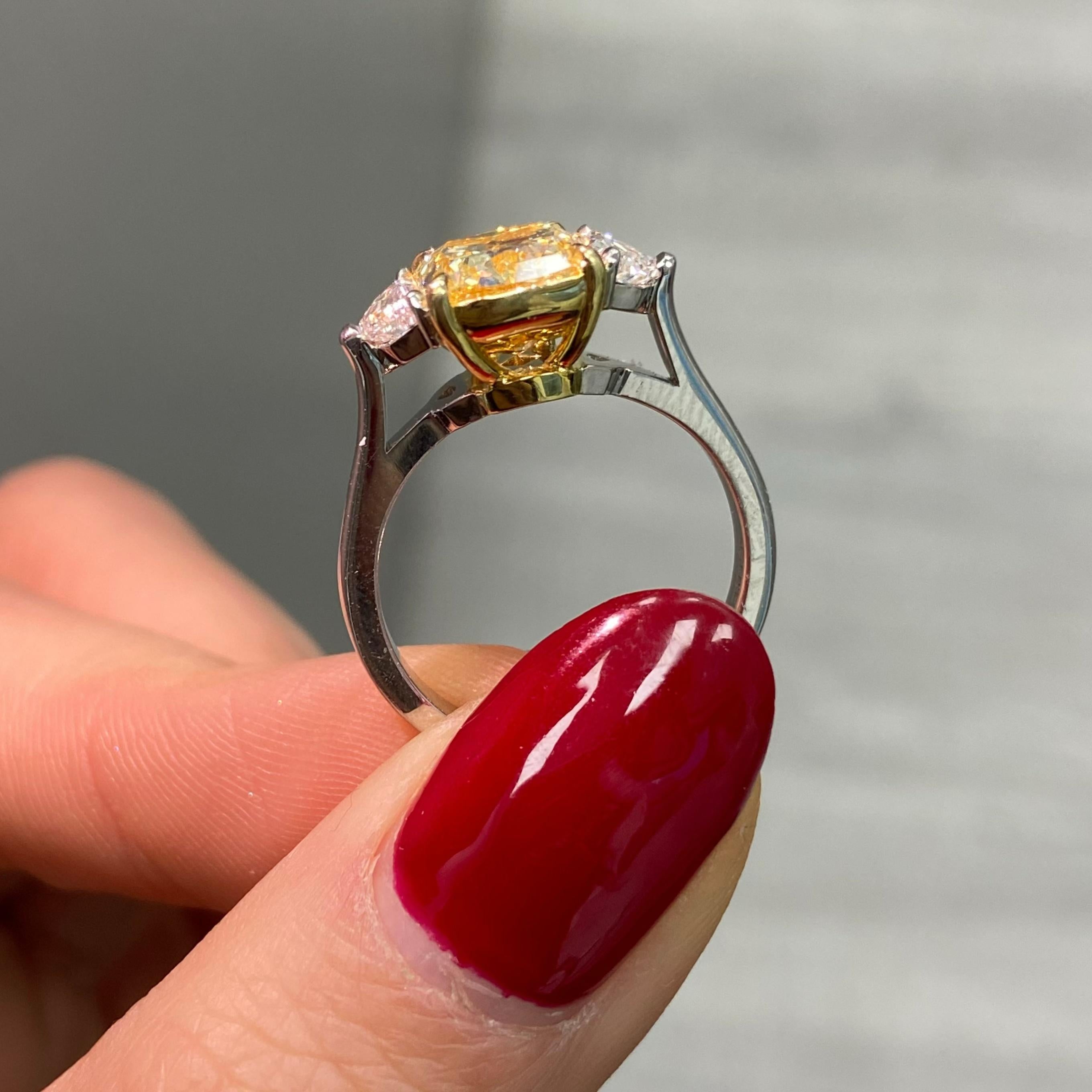 This elegant 3-carat Fancy Yellow three-stone engagement ring combines timeless beauty with rare sophistication. At its center is a GIA-certified cushion-cut Fancy Yellow diamond with VVS1 clarity, showcasing exceptional brilliance and a vibrant