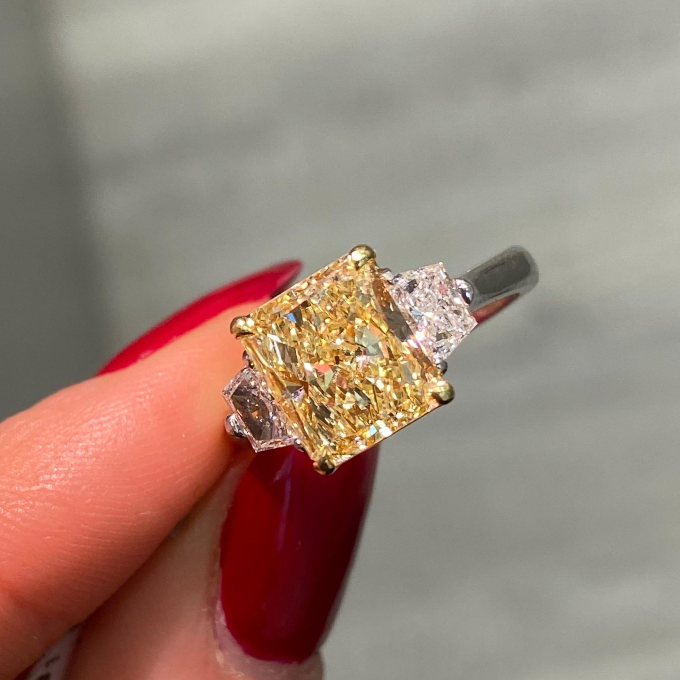 This 3-carat Fancy Yellow radiant-cut diamond engagement ring is a stunning combination of rarity and elegance. The center diamond is GIA-certified with an elongated radiant cut that highlights its exceptional proportions, creating a graceful