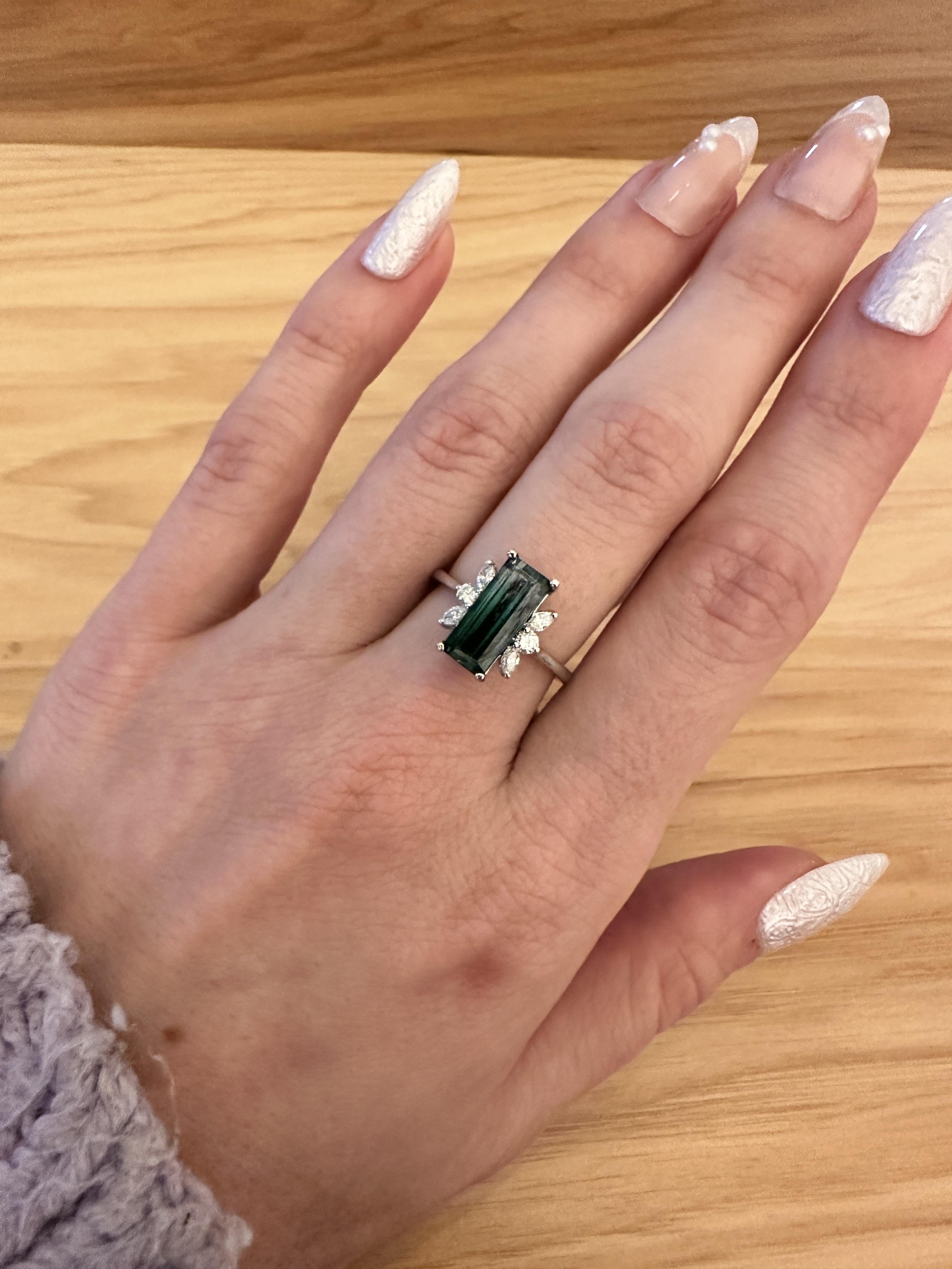 Enjoy this gorgeous 3 carat gradient Indicolite Tourmaline set in one of our custom designs. Crafted in solid 14K White Gold, this stunning ring features a rare 12x5mm emerald-cut Indicolite Tourmaline and sparkling Earth Mined Diamonds. Elevate any