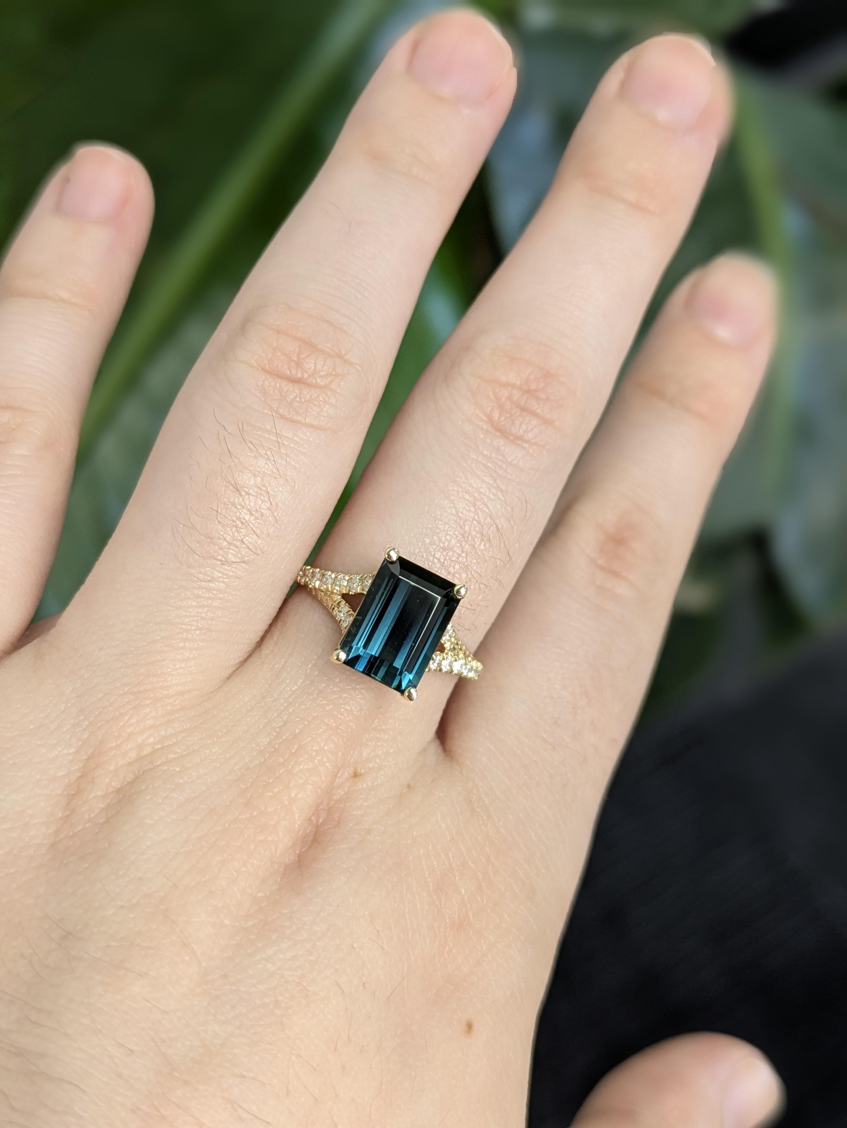 Celebra l'eleganza con questo raffinato anello con tormalina Indicolite e diamanti da 3,06 carati, realizzato a mano in oro giallo massiccio 14k. La pietra centrale con taglio a smeraldo (10x7 mm) brilla di ipnotici riflessi verde acqua,