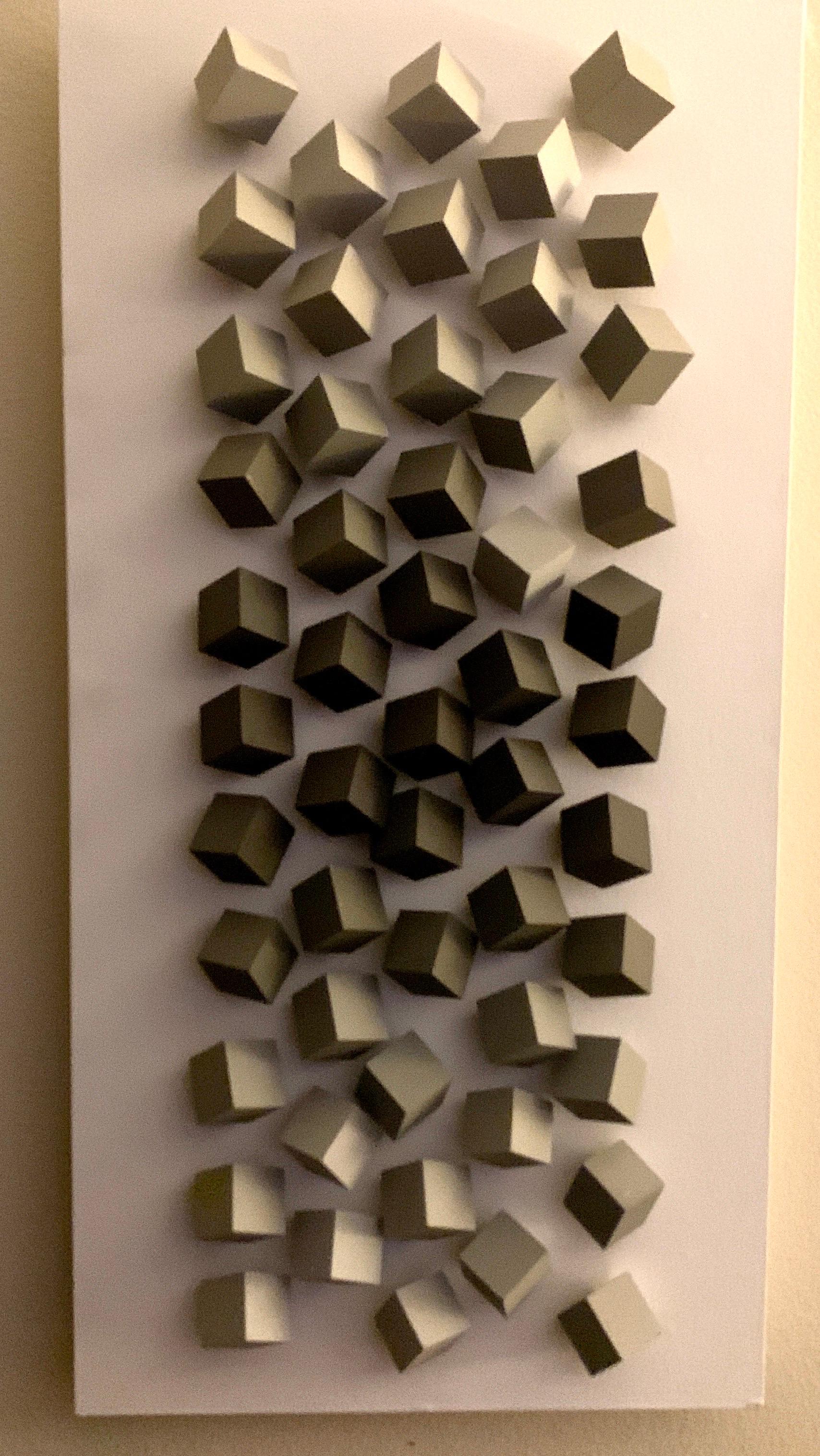 We are in love with this artists work. Based and working in his studio in Brazil., Cícero Silva created this limited edition piece with wood cubes painted in shades of grey on a white painted board. The piece has a very 3 D quality look to it and