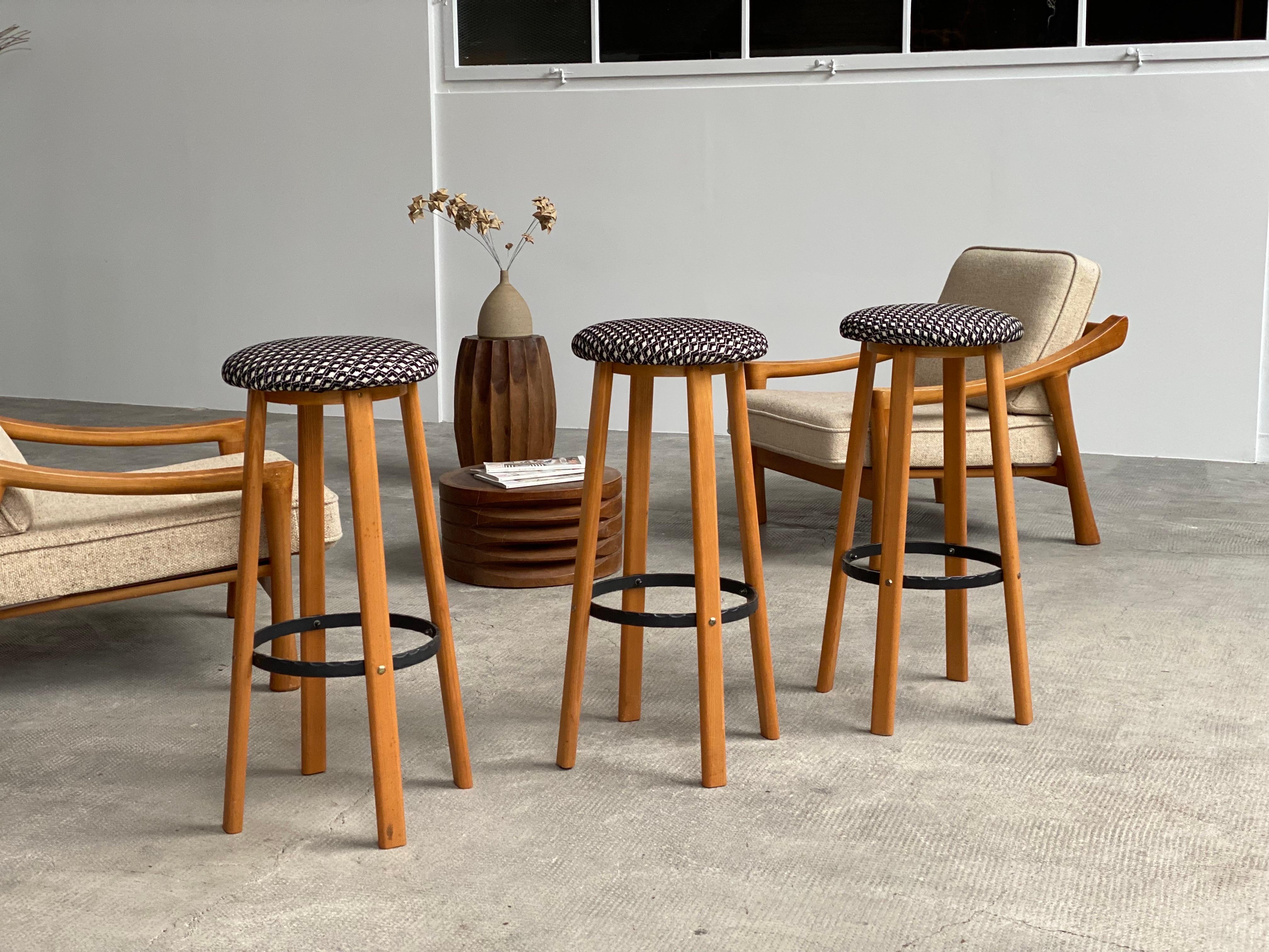 Set of 3 beautiful bar stools made from solid ash wood, featuring a wrought iron ring and newly reupholstered with high-quality fabric. Made in Germany, 1970s.

Country: Germany
Year: 1970s
Materials: Ash wood, iron, textile

Dimensions:
Height: 82