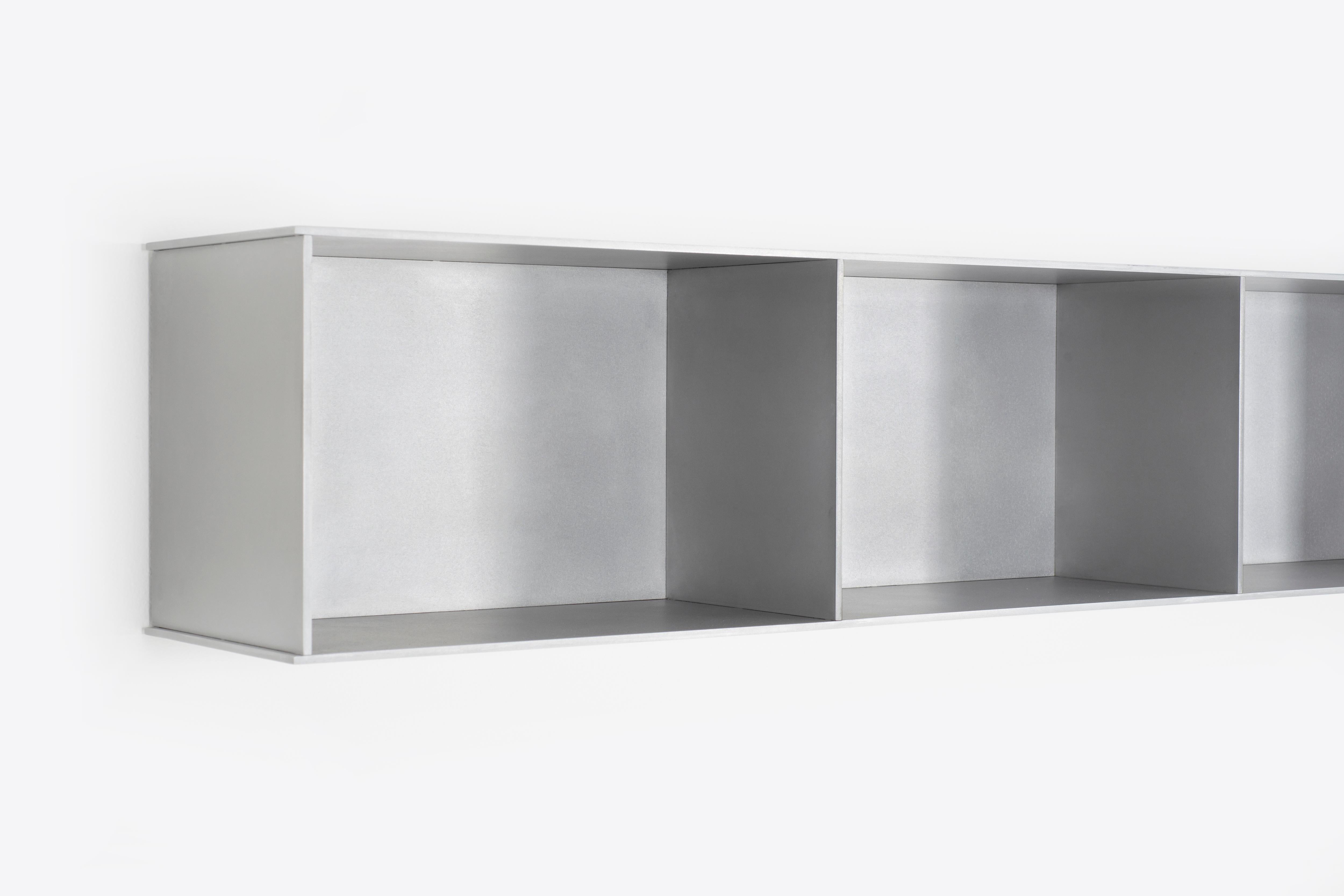 L'étagère murale Minimalist 3G, d'une largeur de 54 pouces, est sculptée dans de l'aluminium poli à la cire d'une épaisseur de 1/4 de pouce. Chaque étagère est dotée d'un profilé en U soudé qui s'étend sur toute la longueur de l'étagère et se monte