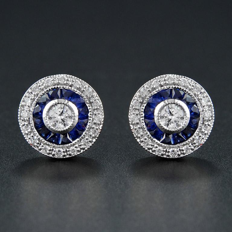 These Art-Deco stud earrings are completely spectacular! The vibrant color stone are specialty cut to surround the excellent round brilliant cut center diamond, which is in a thin bezel with mil-grain detail. 14K White Gold. 
Information
Style: Art