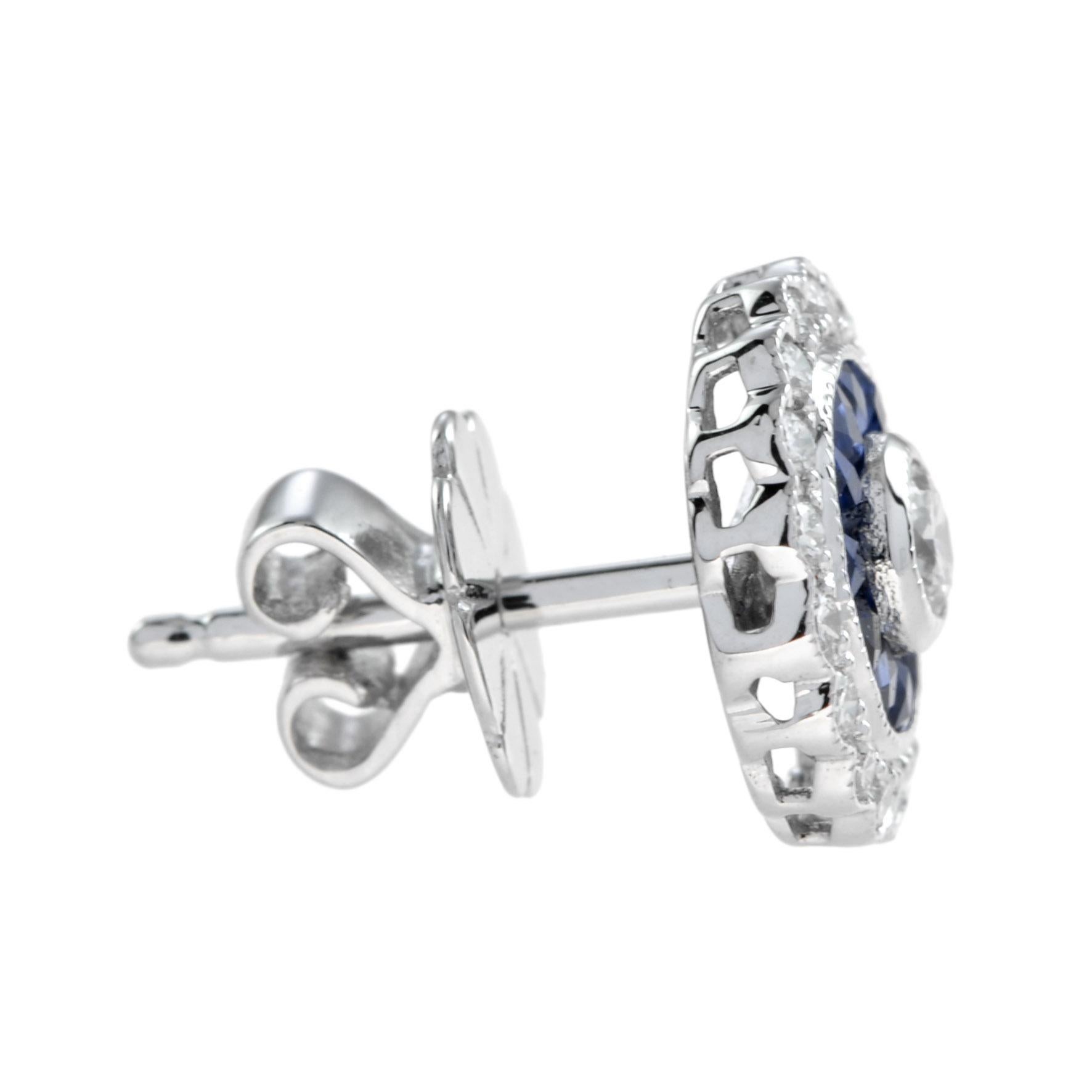A glamorous pair of Art Deco inspired target earrings bezel set with a round brilliant cut diamond in the center. The diamond weighs approx. 0.1 carat and its haloed by French cut sapphires and further diamonds set in 18k gold with millgrain edging.