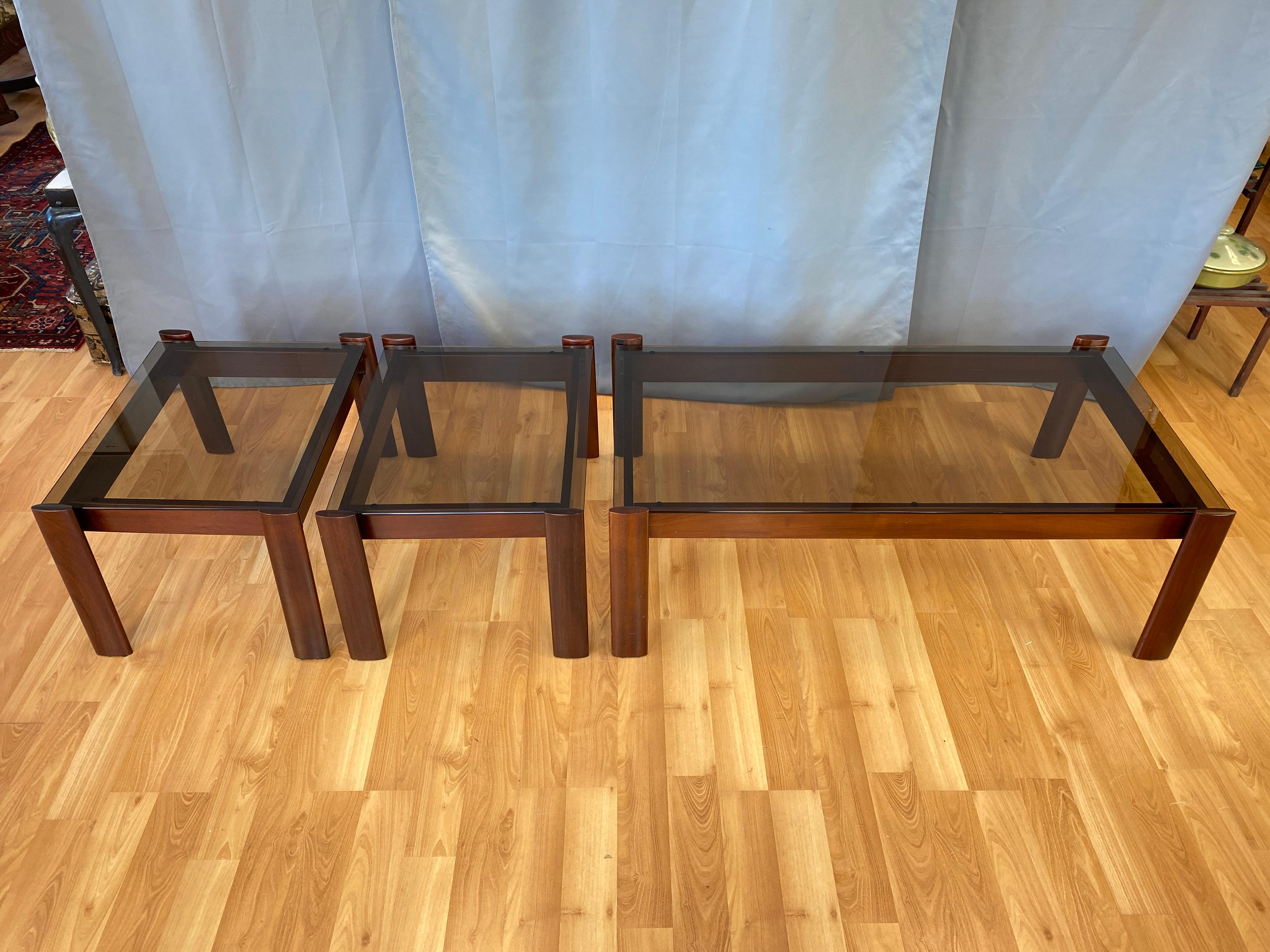 Offered is a three piece set of a Percival Lafer designed coffee and end tables in Jacaranda Rosewood, all have their original smoke glass tops.

Measurements for the coffee table below, the end tables are 27 3/8 x 20, top of the legs 15 1/2, top