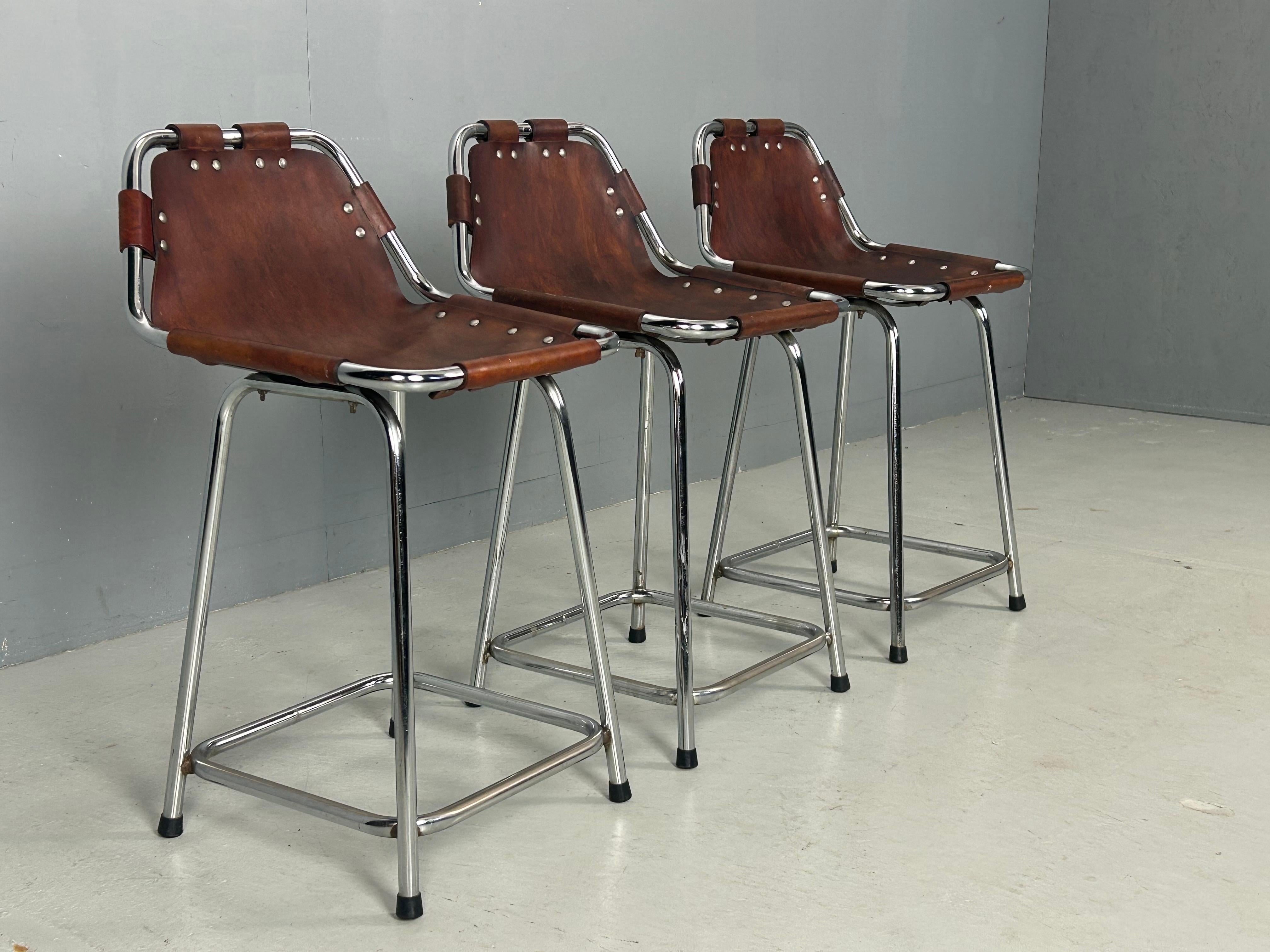 Barhocker, entworfen von Charlotte Perriand für das berühmte Skigebiet Les Arcs in Frankreich in den 1960er Jahren. Jeder Hocker besteht aus einem verchromten Metallrohrgestell und einer Sitzfläche aus cognacfarbenem Leder, das im Laufe der Jahre