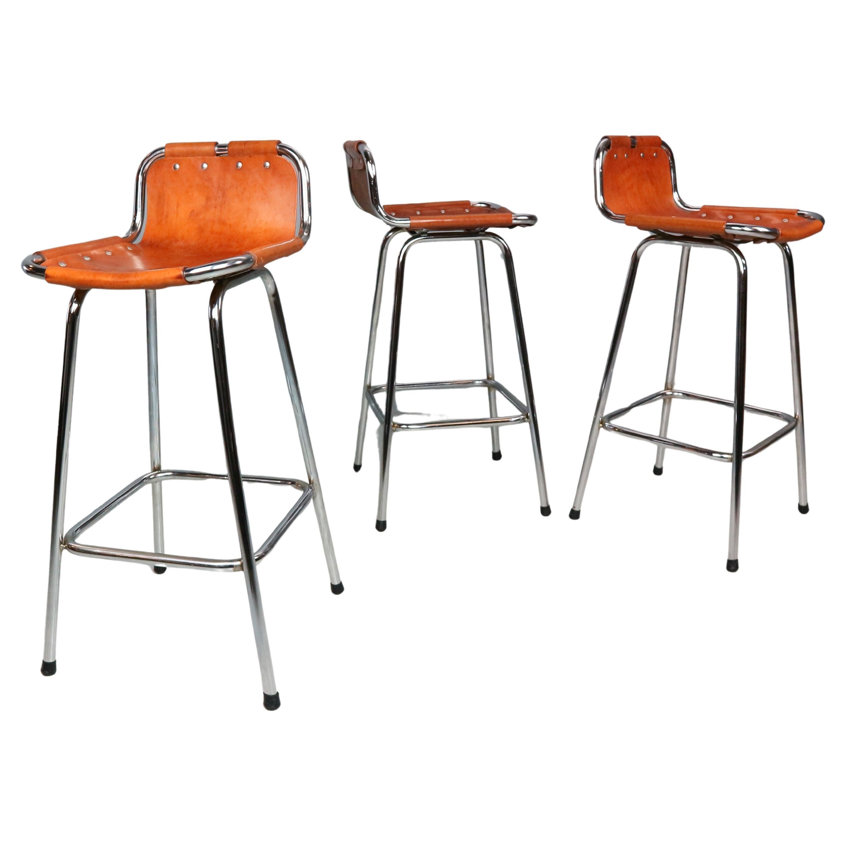 Bar stools designed by Charlotte Perriand for the renowned Les Arcs Ski Resort in France during the 1960s. Each stool features a chrome-plated tubular metal frame and seats crafted from rich cognac leather, which has aged beautifully over the years