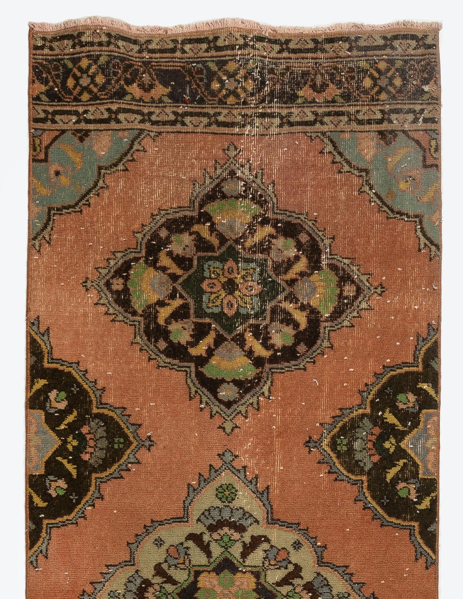 A vintage runner rug from Turkey. It is made of medium wool pile on wool foundation and features multiple full and half medallions decorated with floral motifs in brown, light green, salmon pink and slate blue against a rust-colored field.
It has