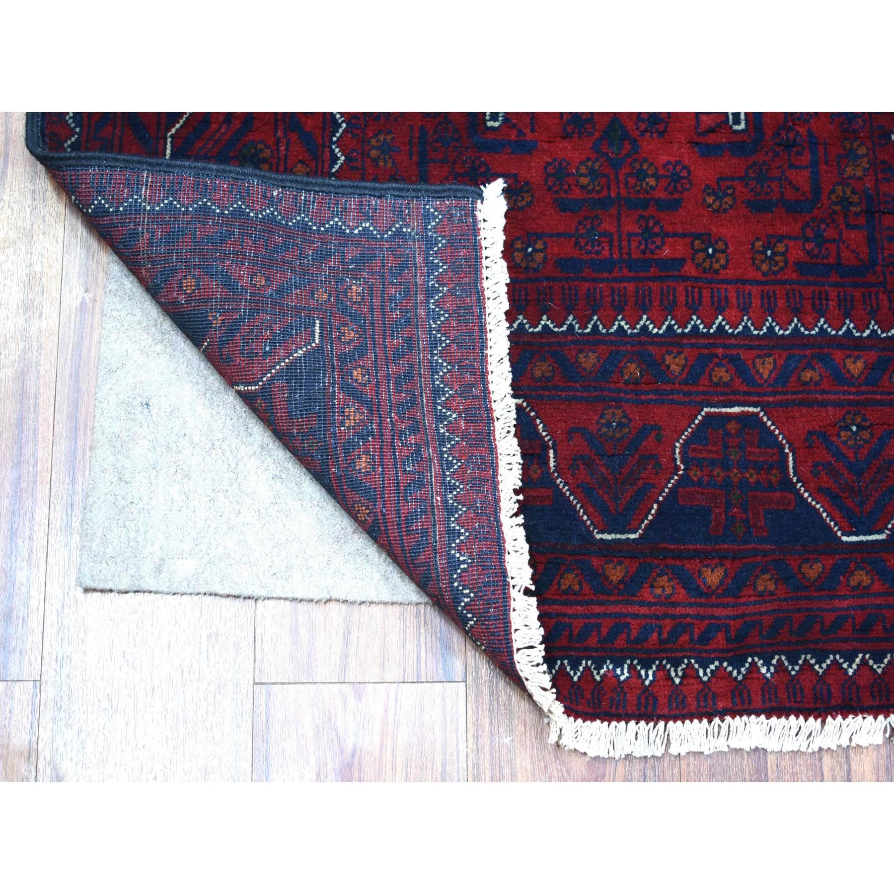 Il s'agit d'un véritable tapis d'Orient, unique en son genre, d'un rouge profond et saturé avec des touches de bleu marine, Afghan Khamyab avec un design géométrique, en laine douce nouée à la main, avec un chemin de table. Il a été noué pendant des