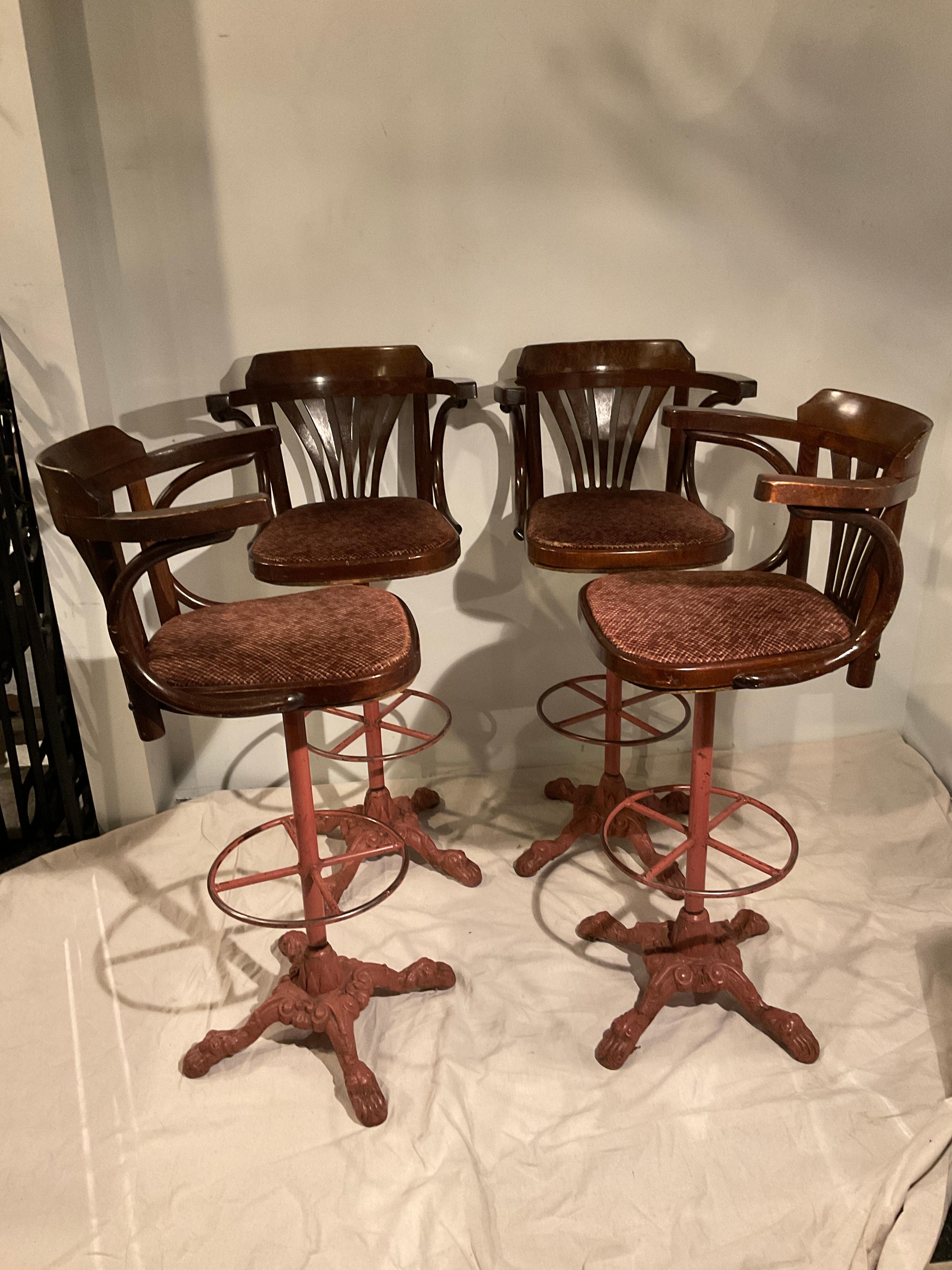 Four 1920s wood swivel bar stools on iron bases. One chair has veneer missing, as shown in image 2.