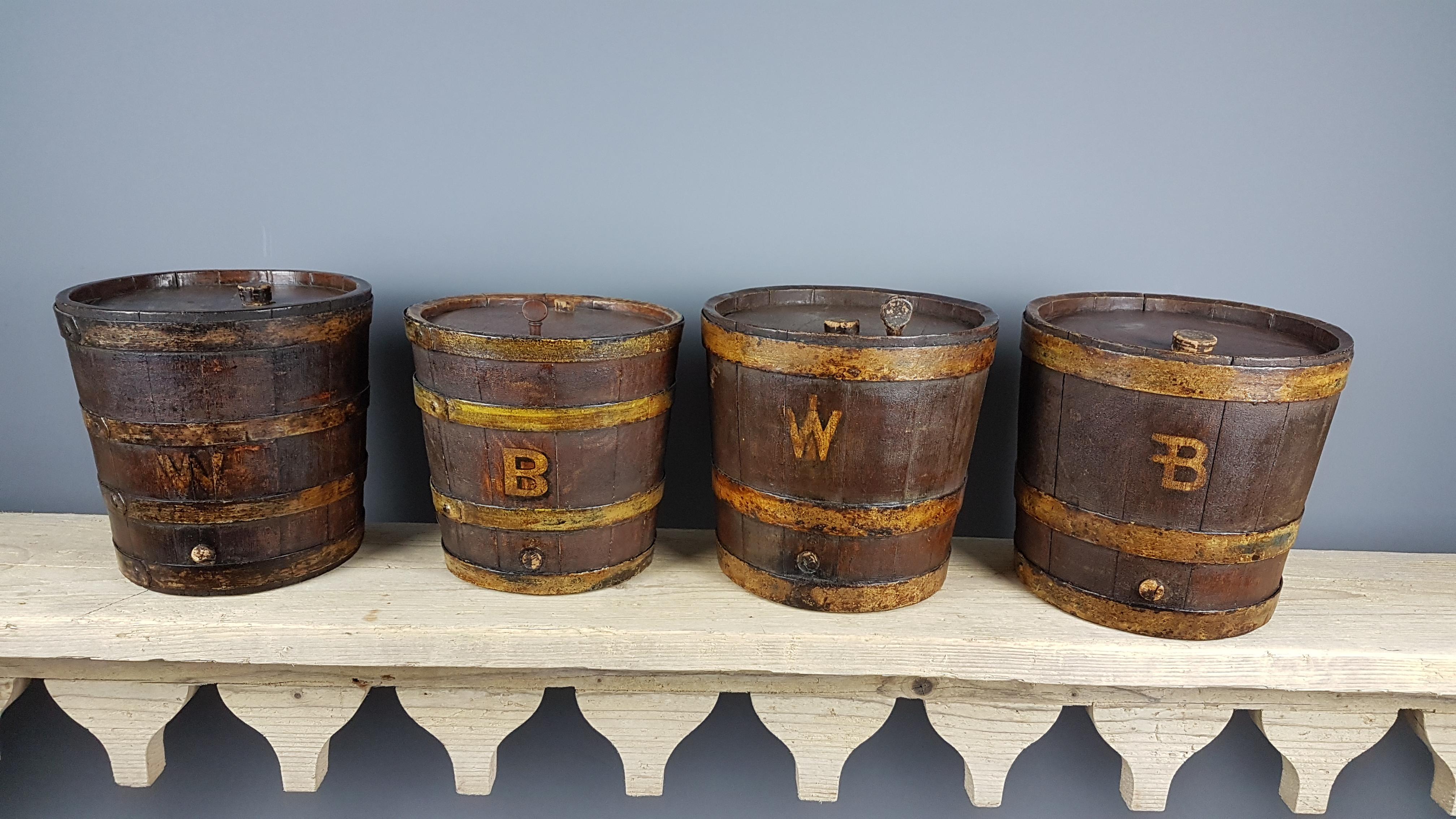 4 unusual and decorative 19th century oak coopered barrels with painted iron bandings in their original scumble paint finish which oddly enough is a faux oak paint with painted letters. Two have a 'W' which I assume to be for whiskey and two have a