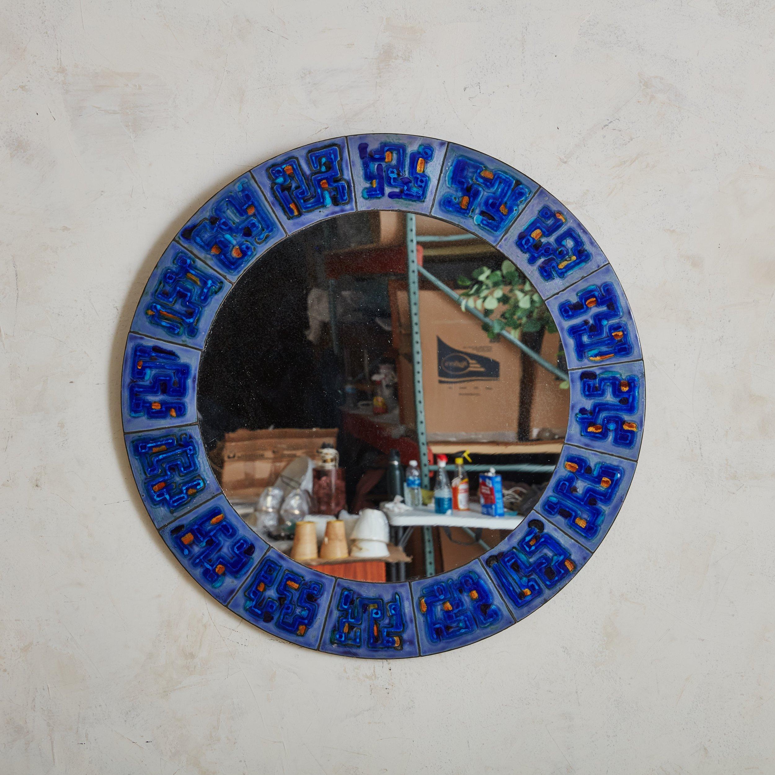 A Scandinavian Modern round wall mirror by Bodil Hagedorn Eje. Daughter of painter Thorvald Hagedorn-Olse, Bodil Eje was a Danish artist from the 20th Century who mostly worked with enamel. The mirror’s frame is composed of enameled copper plates