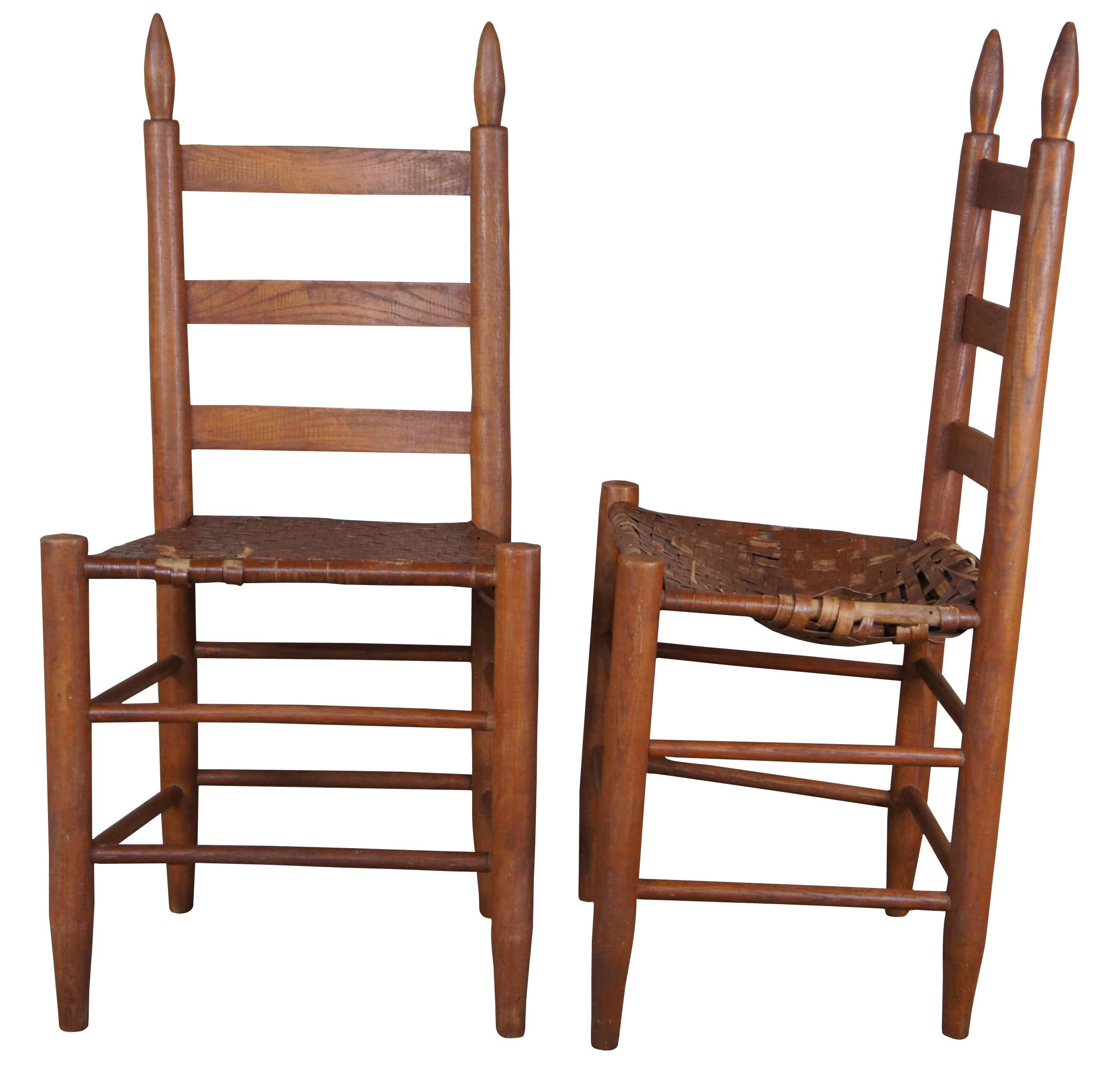 Four vintage pine early American style Shaker ladderback dining chairs featuring rush seats and tall finials.
 