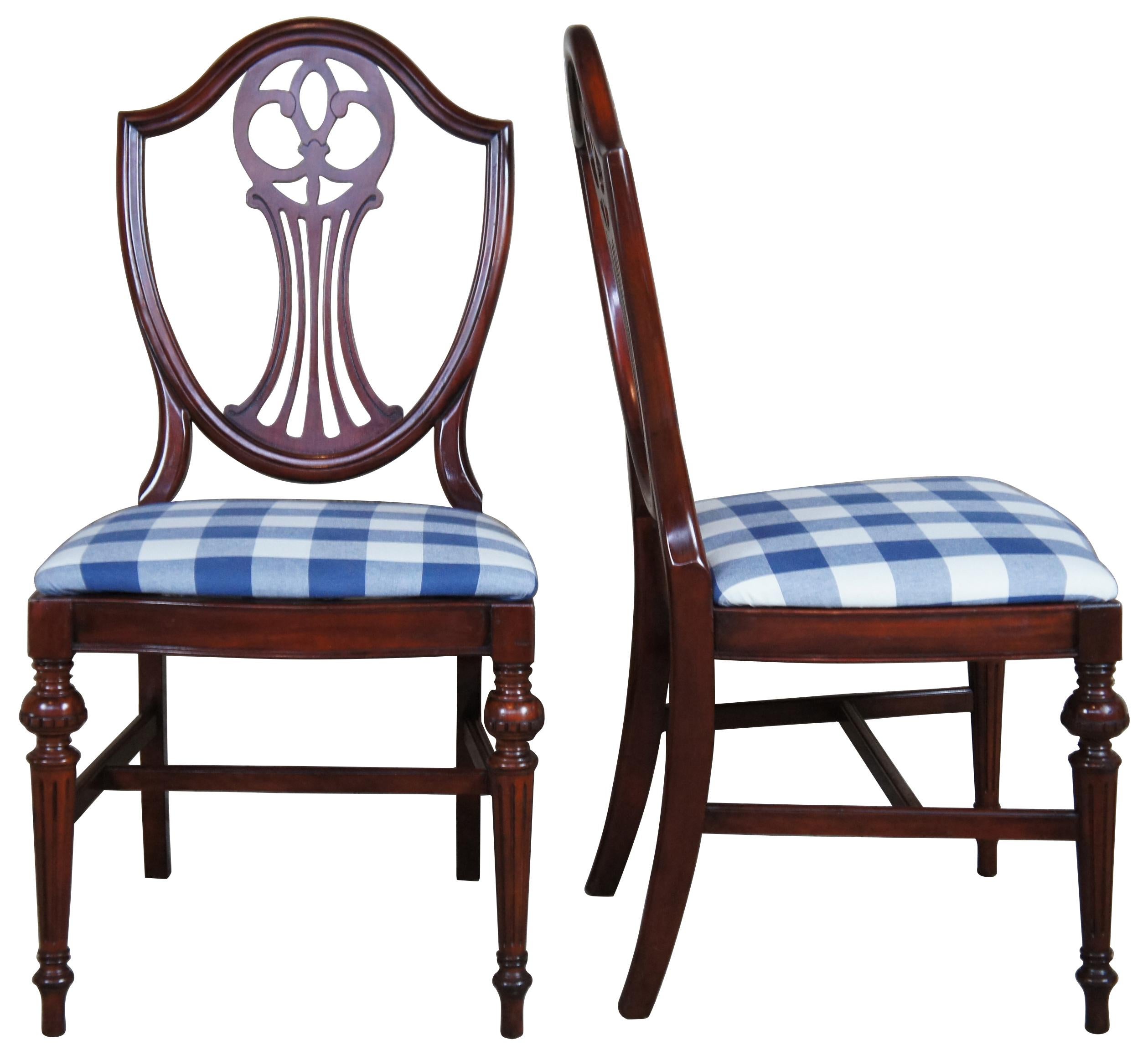 American red mahogany dining chairs, circa 1940s. Features a blend of Sheraton and Hepplewhite styling with a pierced shield back. Upholstered in a white and blue check over turned fluted and tapered legs connected by an H-stretcher leading down to