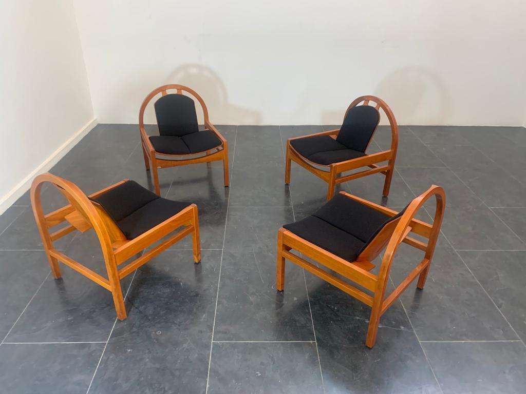 Set of four Argos armchairs by Baumann made in France in the 1980s. Attractive beech structure design with wide, low sloping seat, rounded borders and fine details that hint at quality and identify the company's style. The black fabric upholstery is