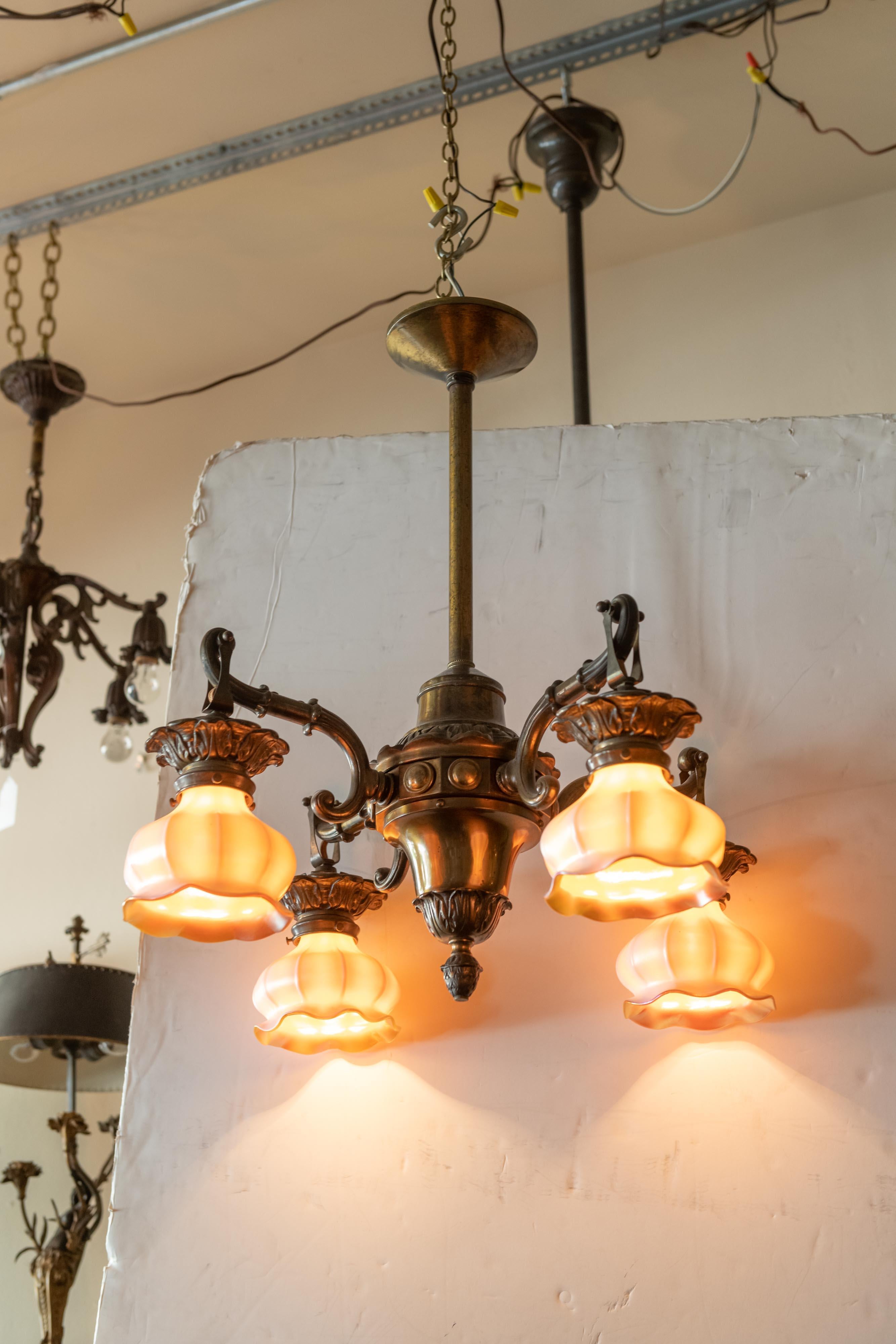 Very handsome richly patinated bronze chandelier with 4 exceptional art glass. While the shades are unsigned, we are attributing them to Steuben Glass Co. The shades change color when lit vs. unlit. They are creamy white when unlit and turn gold