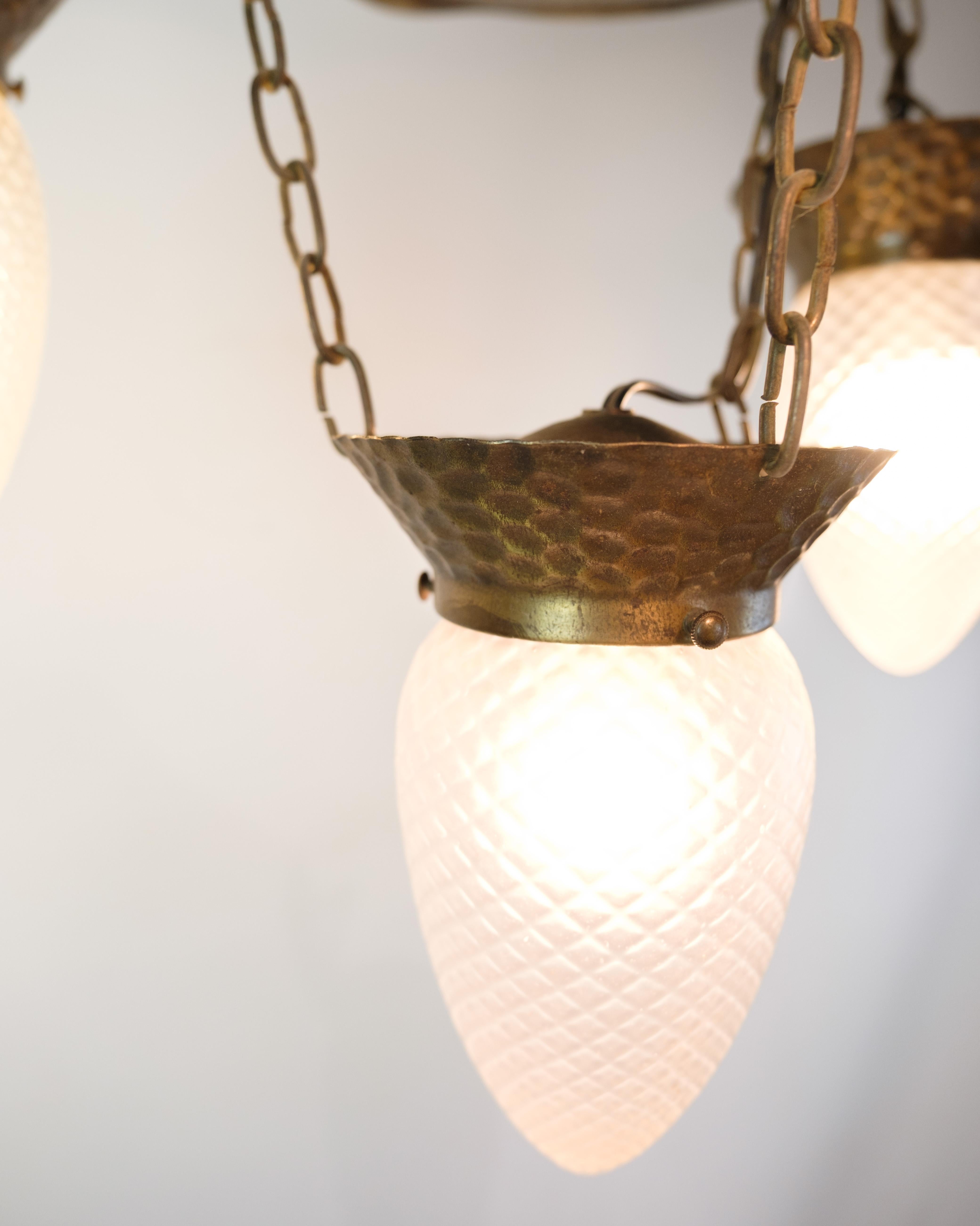 Art Nouveau chandelier from the 1920s in patinated, hammered brass with four arms and teardrop-shaped glass. Elegant classic ceiling lamp.

Period: 1920s
Style: Art Nouveau
Materials: Hammered brass, teardrop-shaped glass
Number of arms: