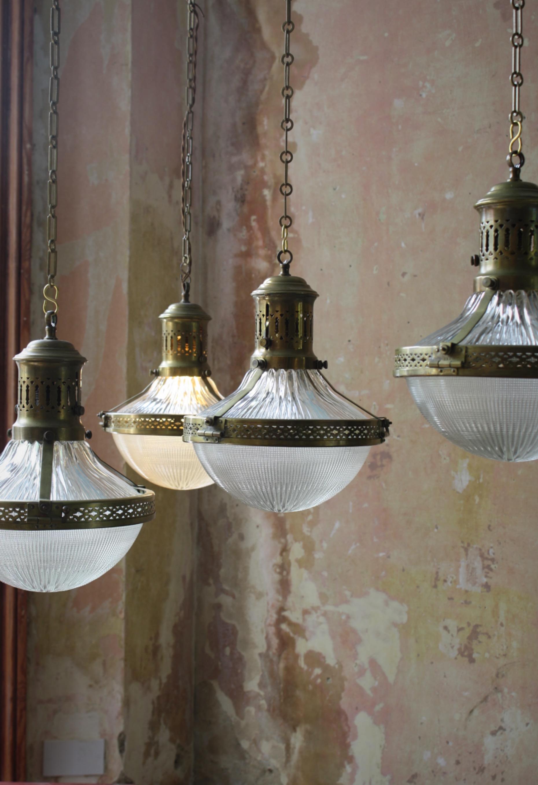 Seldom seen, a matching quartet of early 20th century French caged Holophane pendants.

Each brass cage houses two section of prismatic glass with decorative pierced central band and galleries.

In pristine condition, with age related