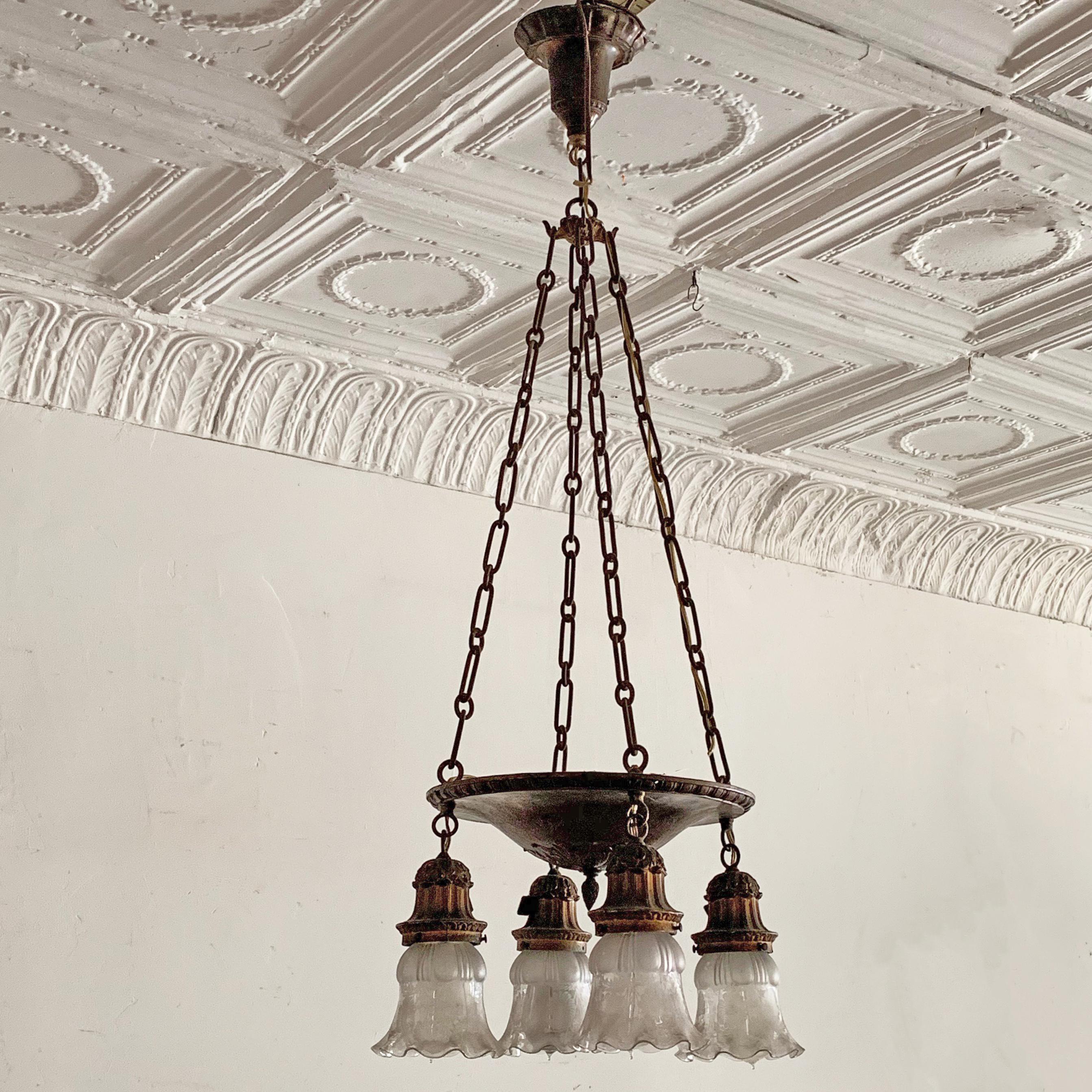 1930s, brass-plated, cast metal, pan chandelier with lovely raised ornamentation features a pan center, suspended by chain with 4 etched glass dropped lights. The each light is wired to accept up to 75 watt bulbs.