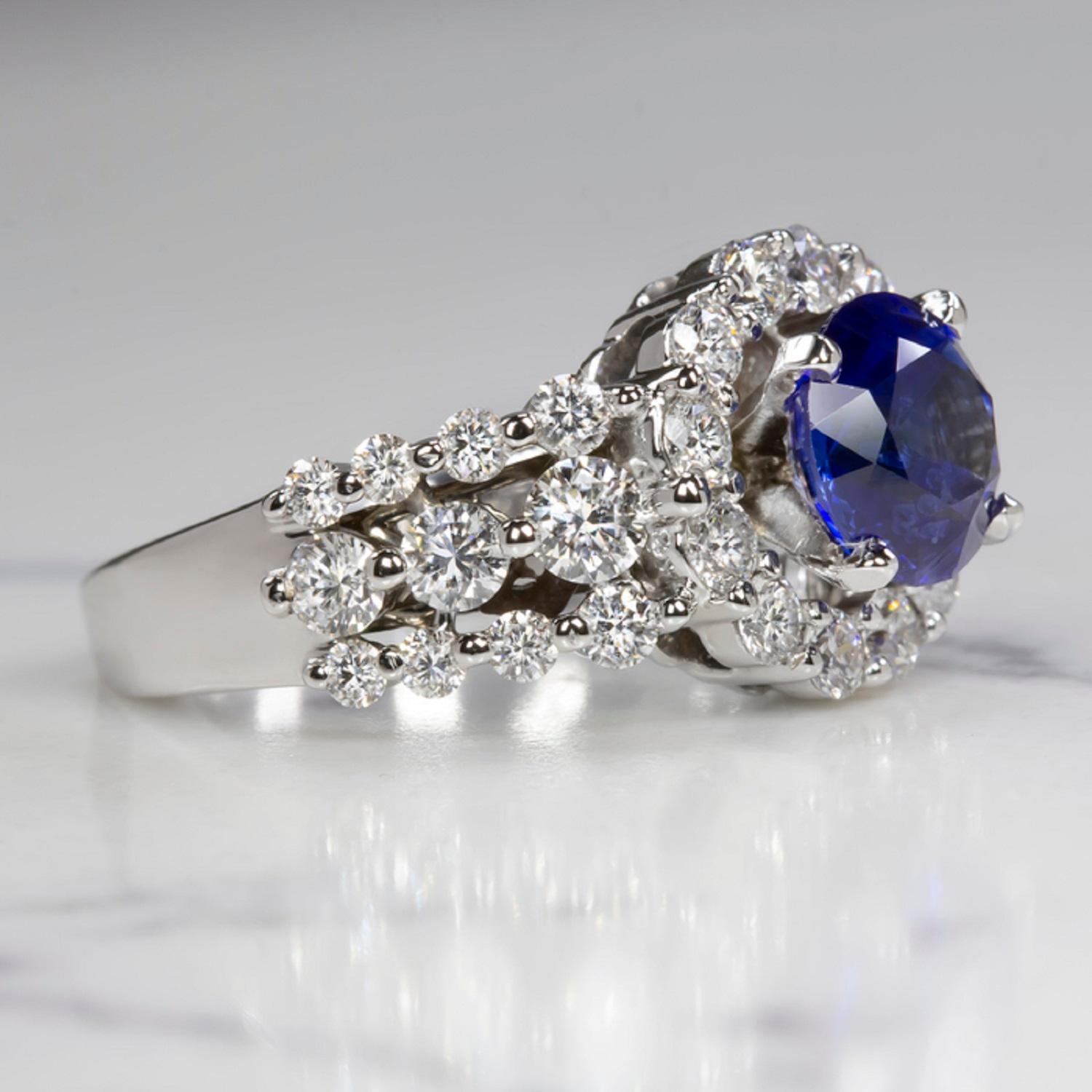 A striking and high quality sapphire and diamond ring has an eye catching, glamorous design featuring a royal blue sapphire surrounded by a halo of vibrant, very high quality diamonds! The large 2.02ct round cut sapphire is a gorgeous royal blue
