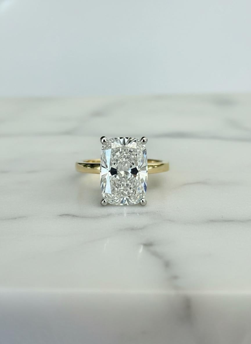 Magnifique et intemporelle, cette bague de fiançailles est ornée d'un superbe diamant brillant modifié en coussin de 4 carats de couleur G et de pureté VS2. Taillé par des experts selon les normes GIA, le diamant présente une brillance